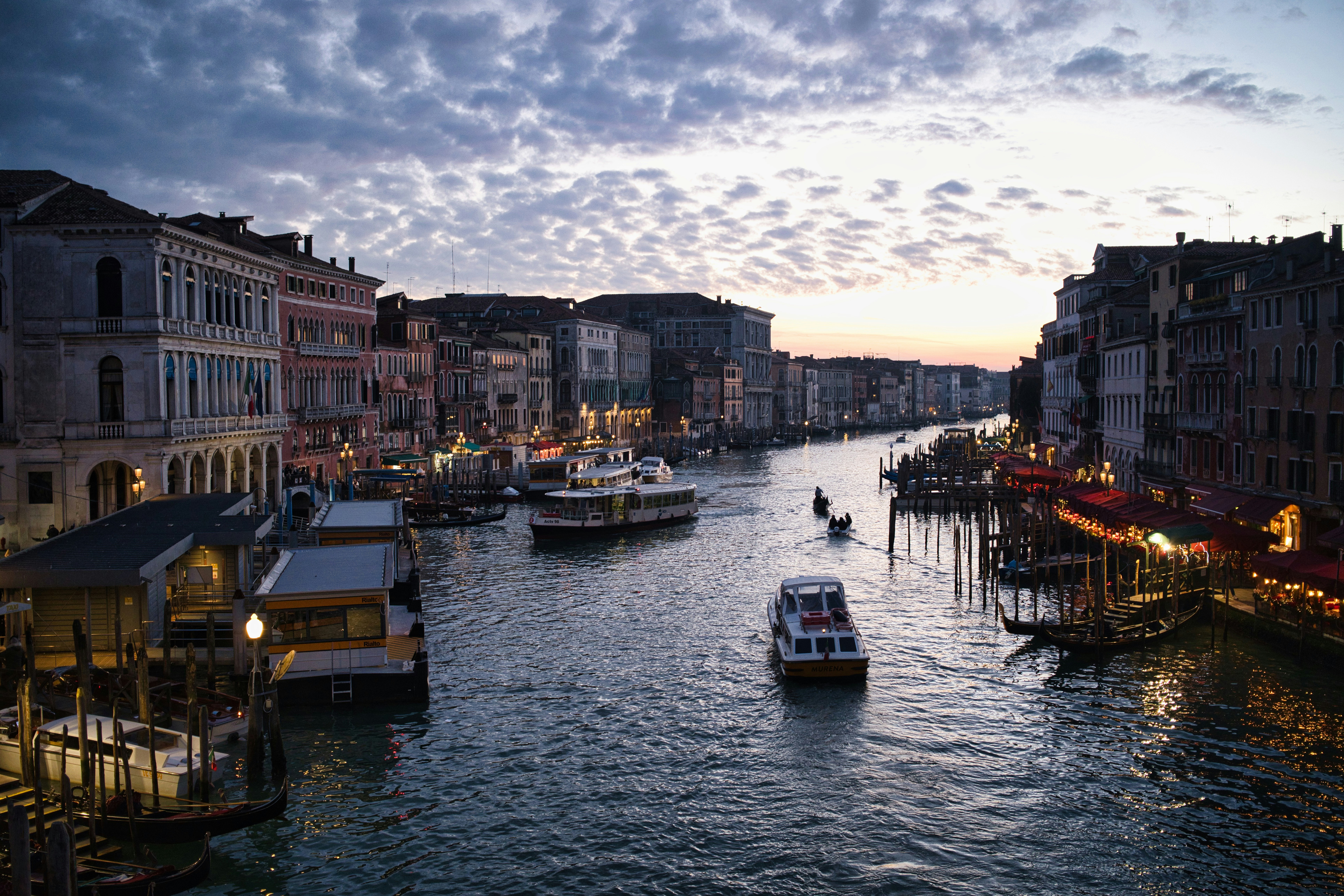 Boats on a canal lined with buildings at dusk.