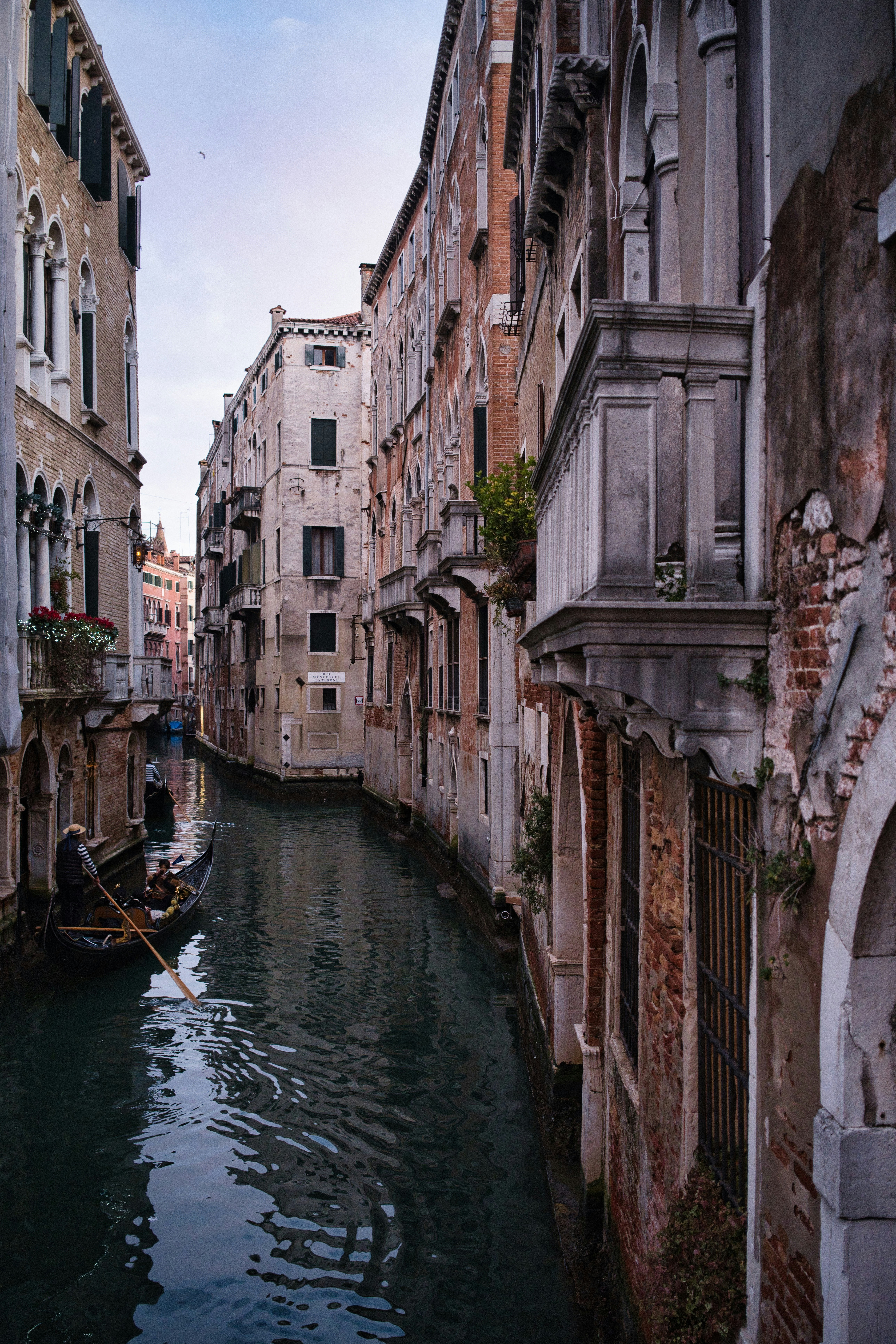 Gondolier navigates a narrow canal in venice.