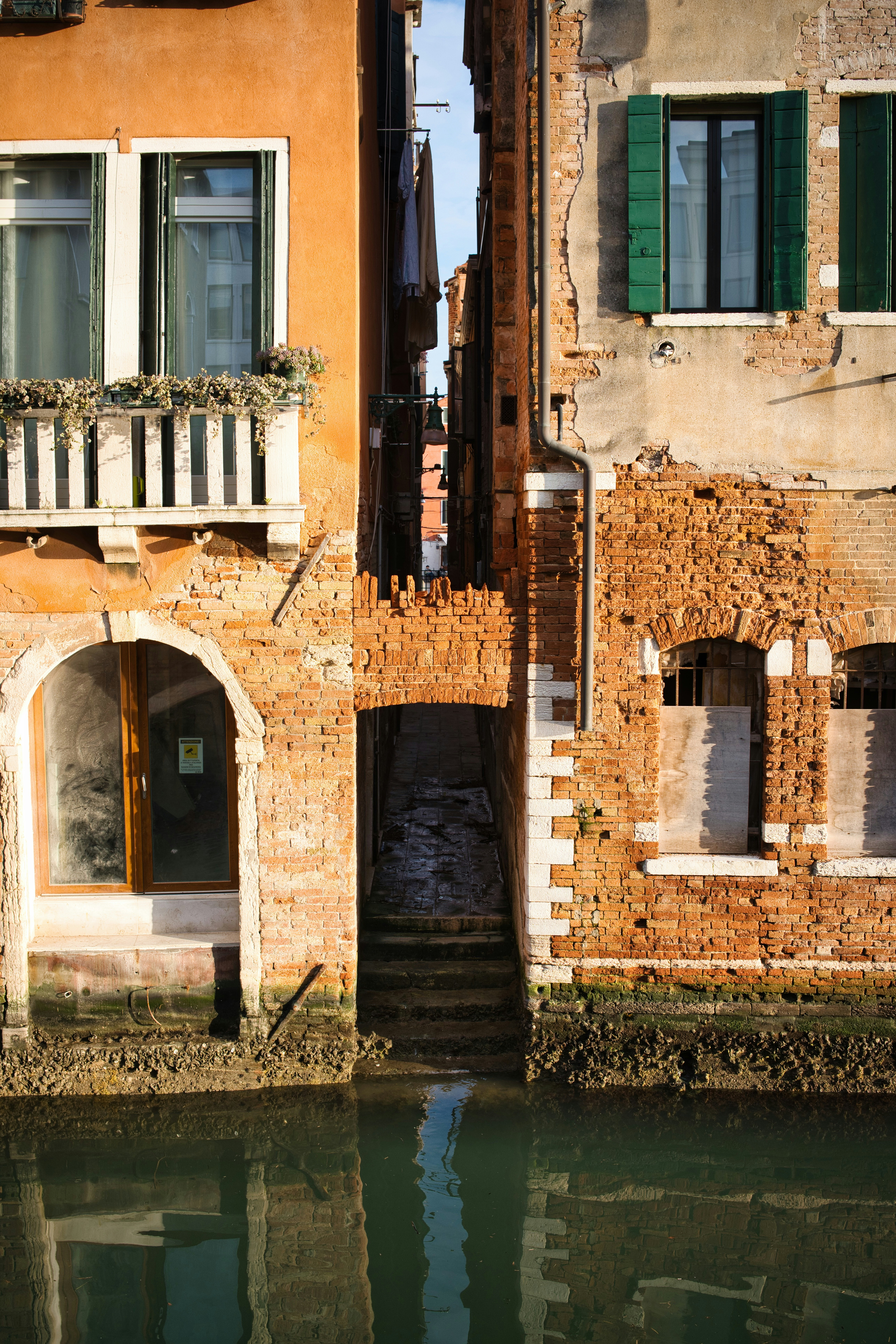 Narrow canal passage between old brick buildings in venice