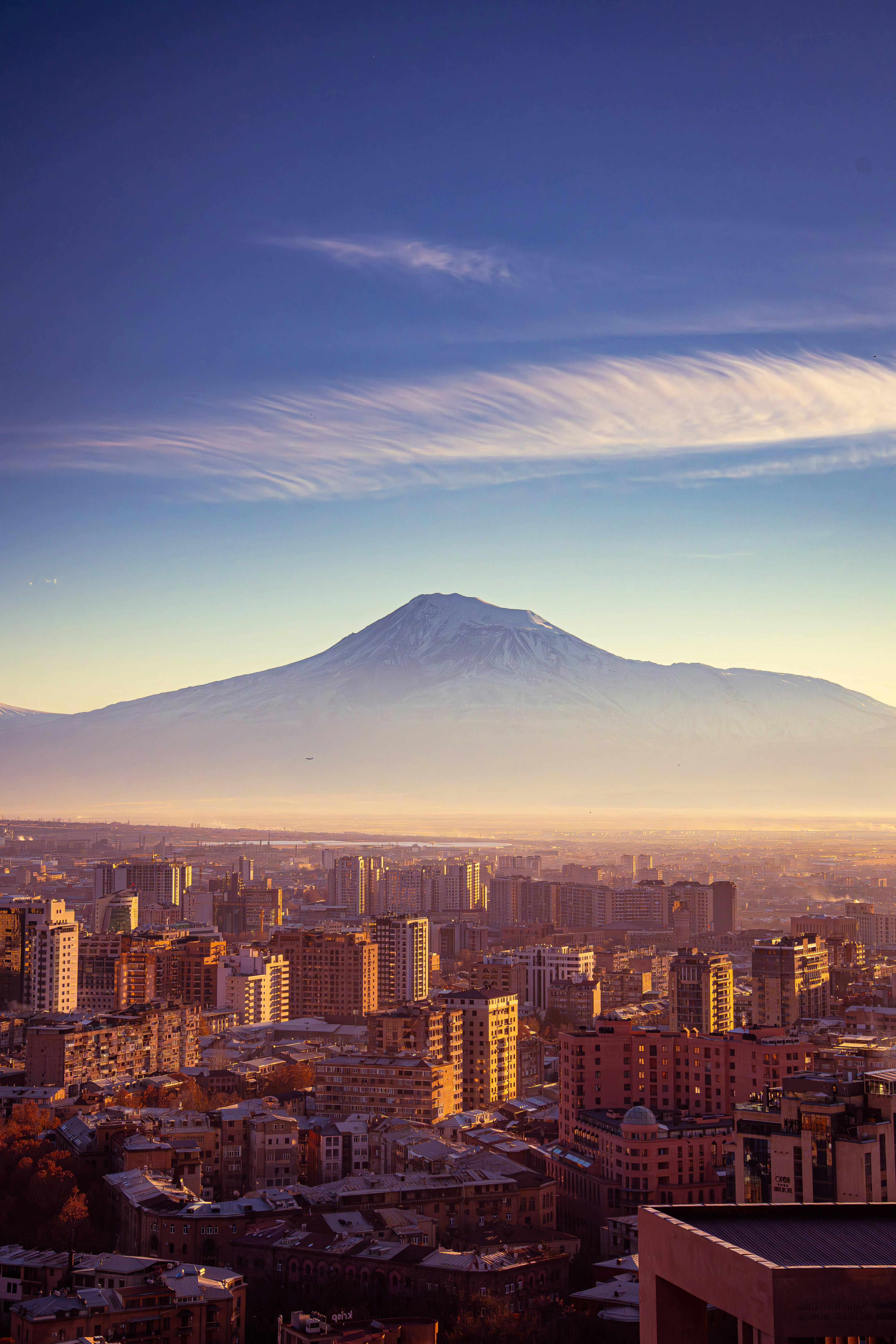 Mountain peak looms over a city at sunrise.