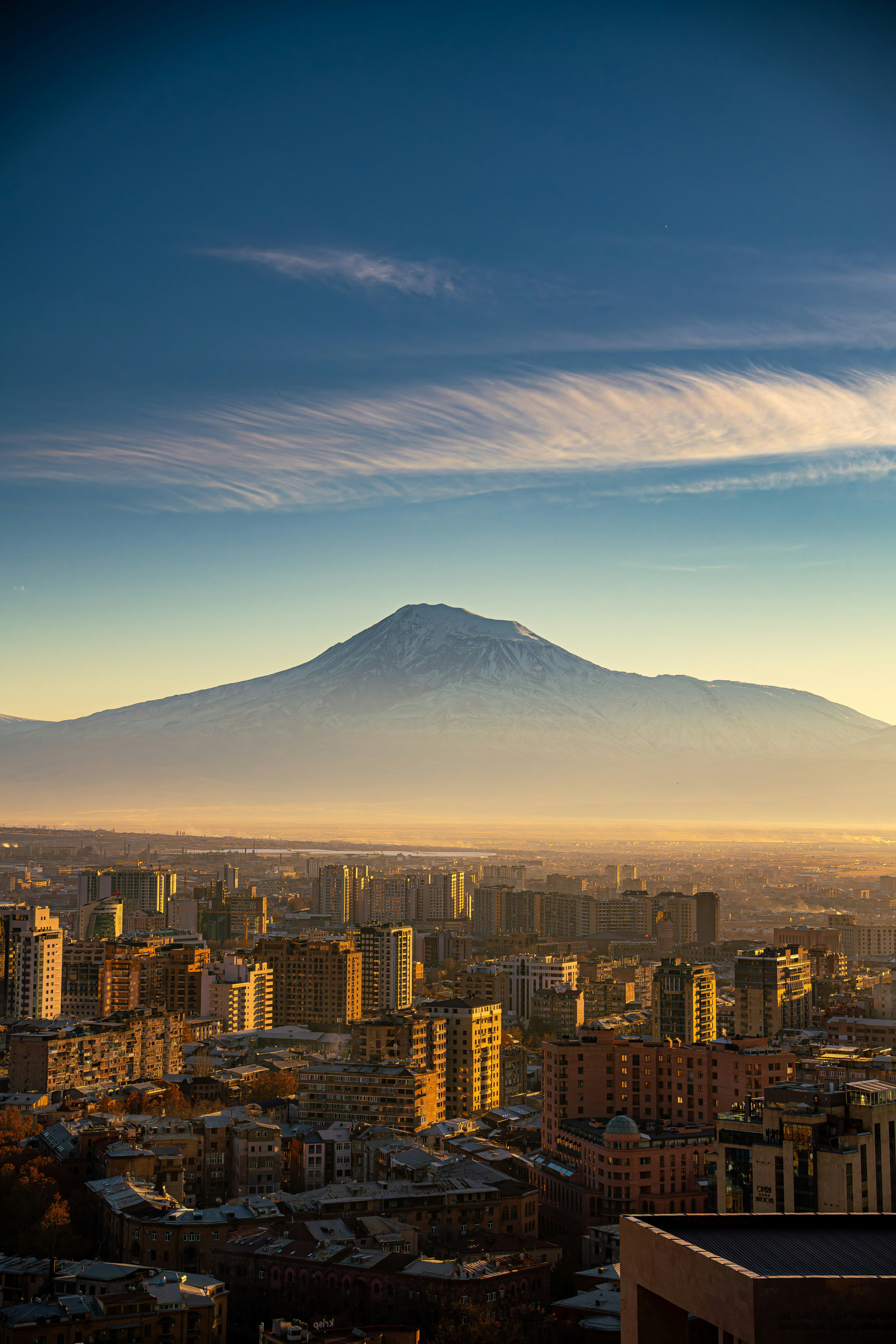Majestic mountain looms over a sprawling city at sunrise.