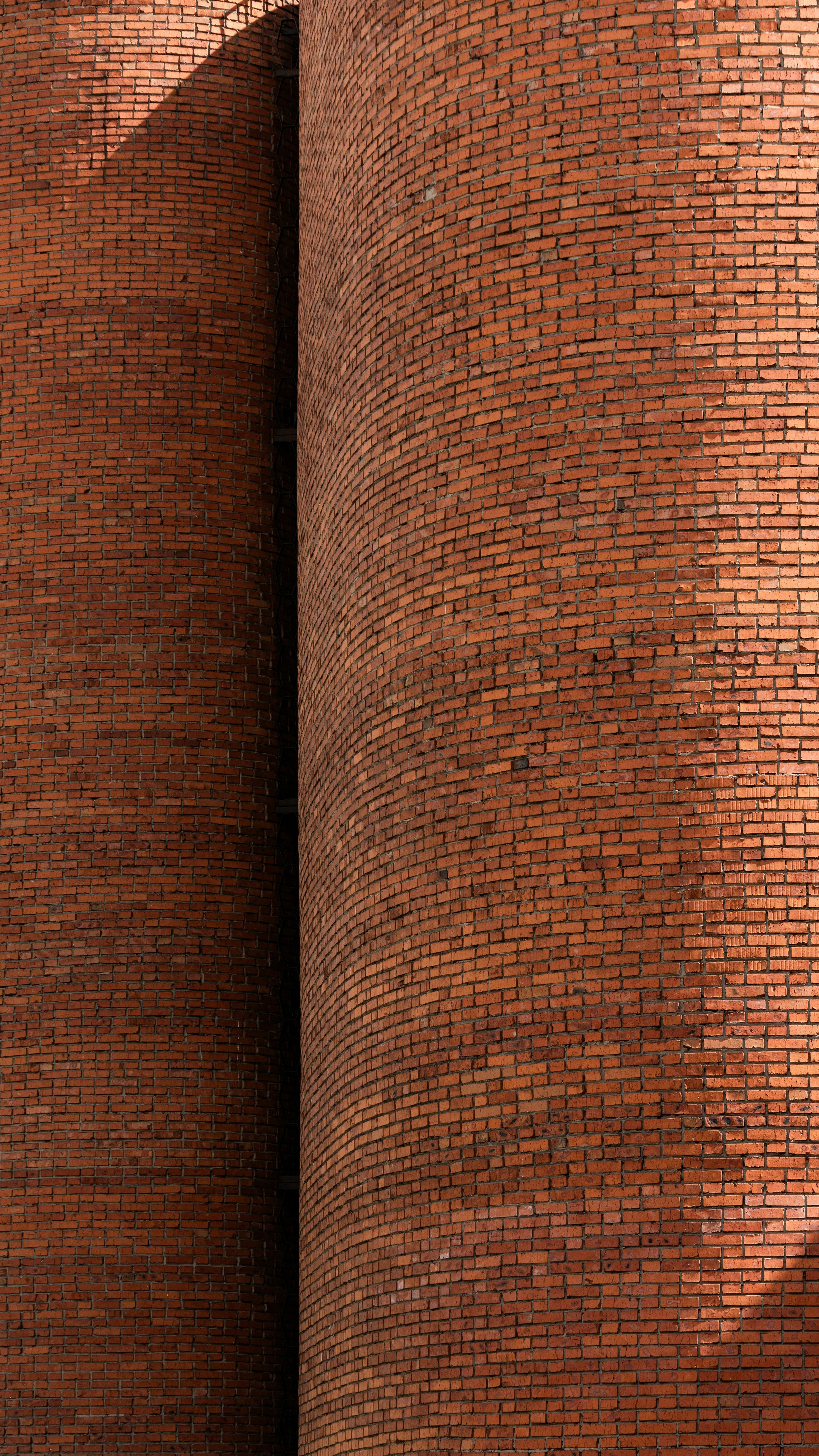 Muro curvo de tijolos vermelhos com sombras dramáticas