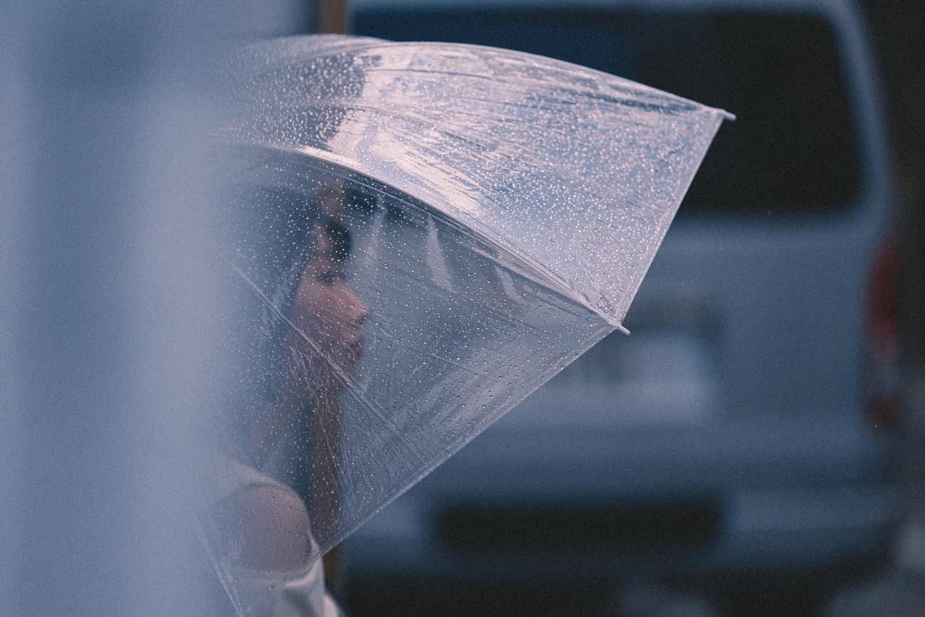 Woman holding a clear umbrella in the rain for a moody portrait photograph
