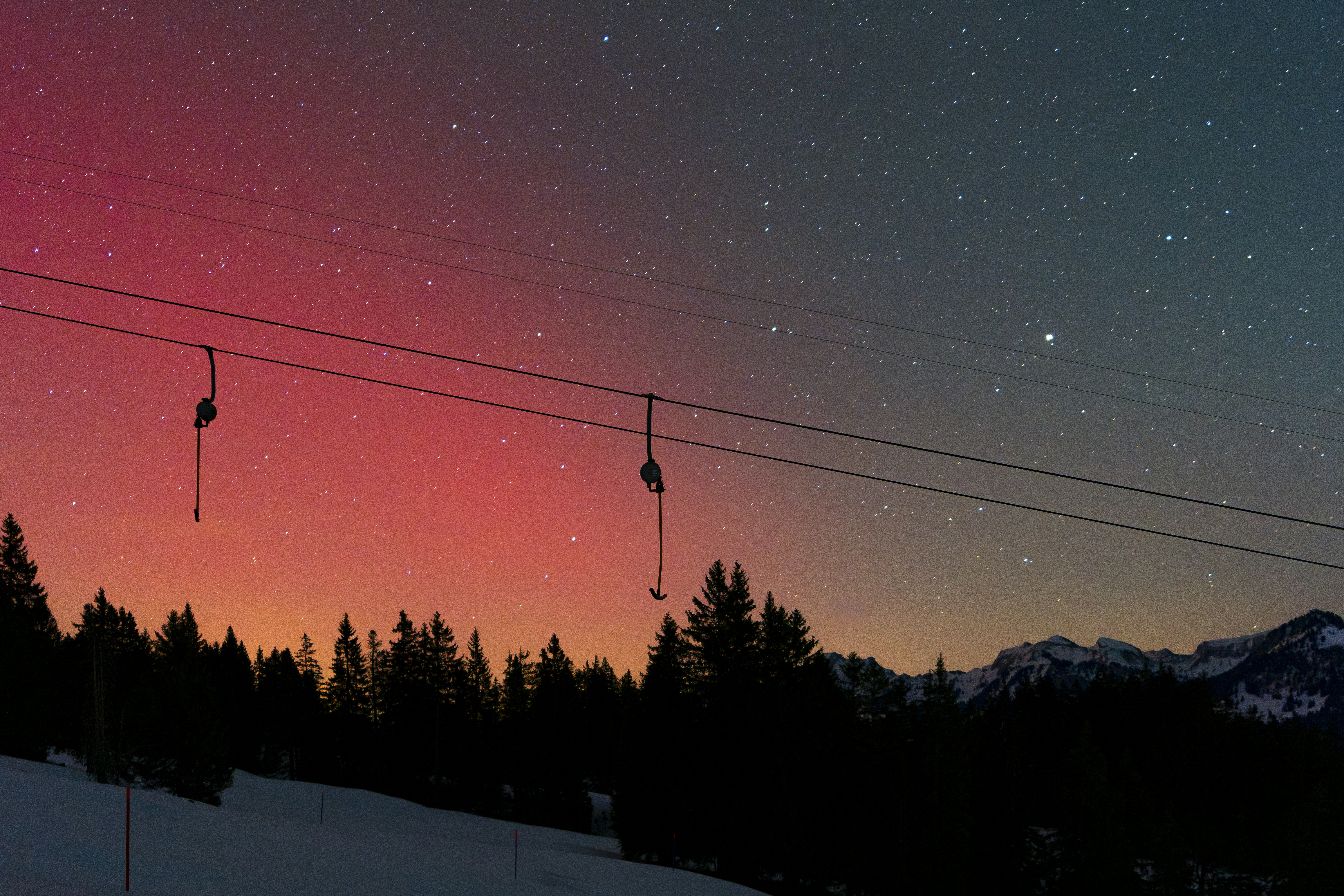 Starry night sky over snowy mountains and trees