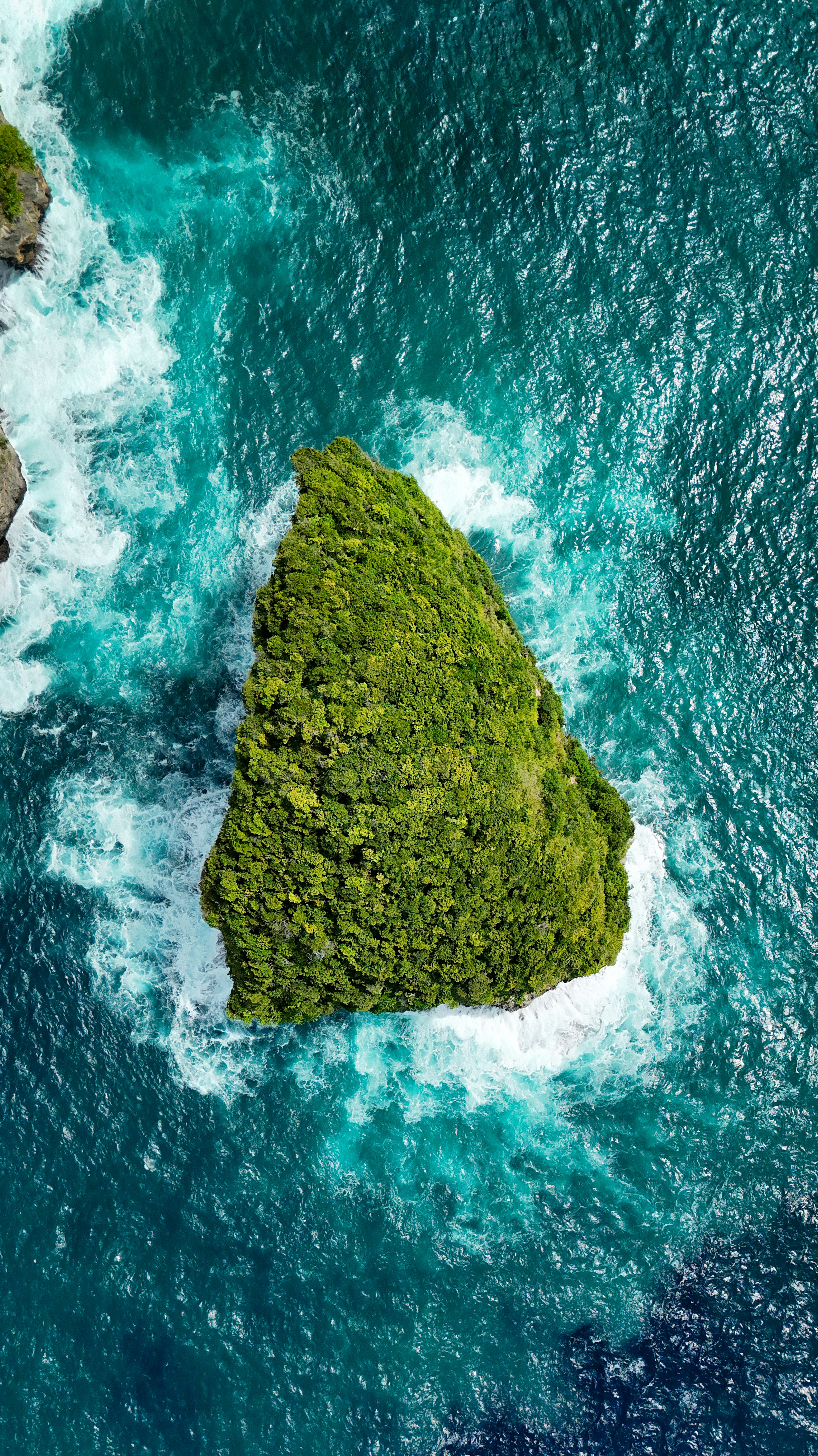 Green island with waves crashing on the shore.
