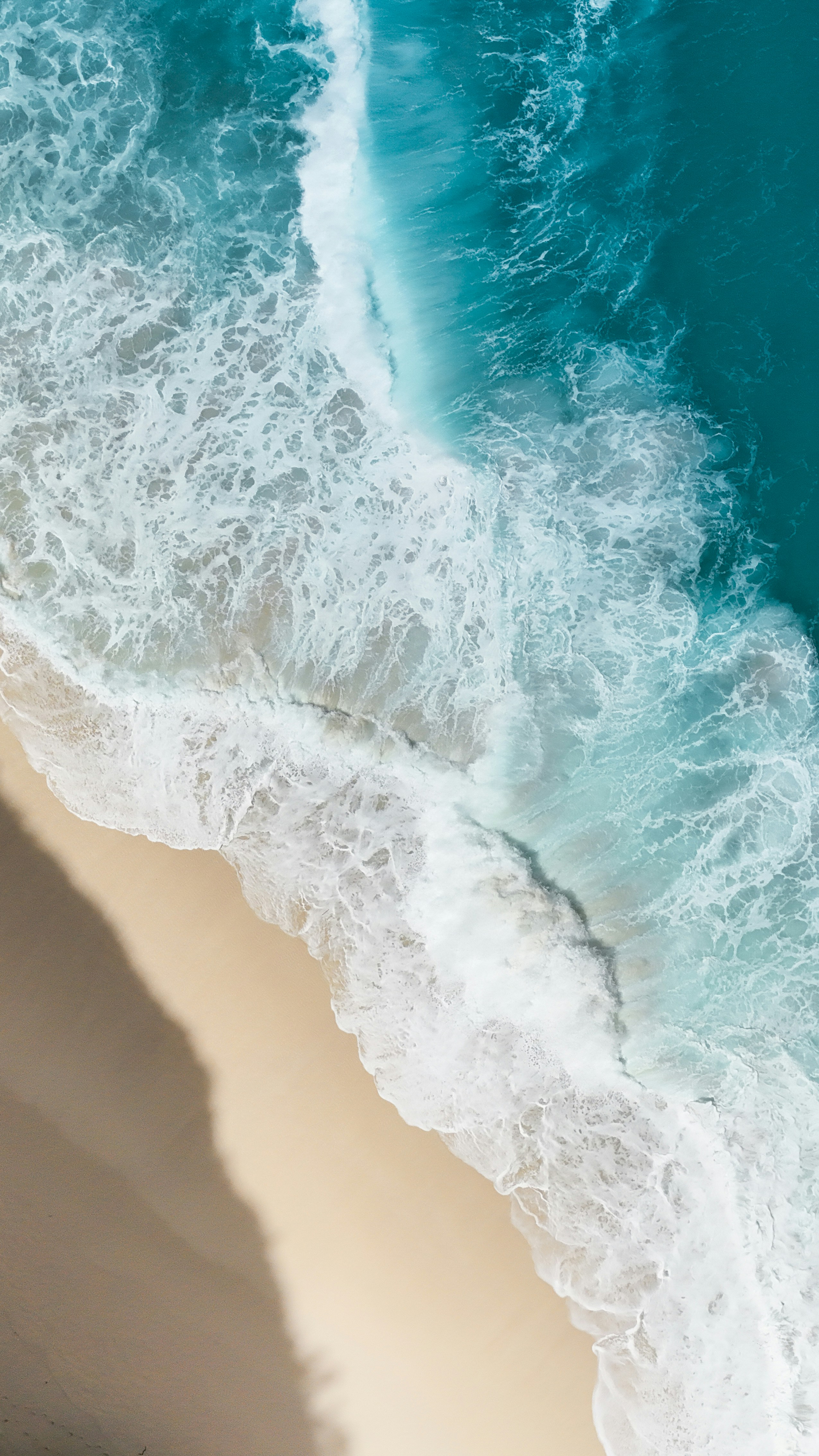 Aerial view of ocean waves crashing on a sandy beach
