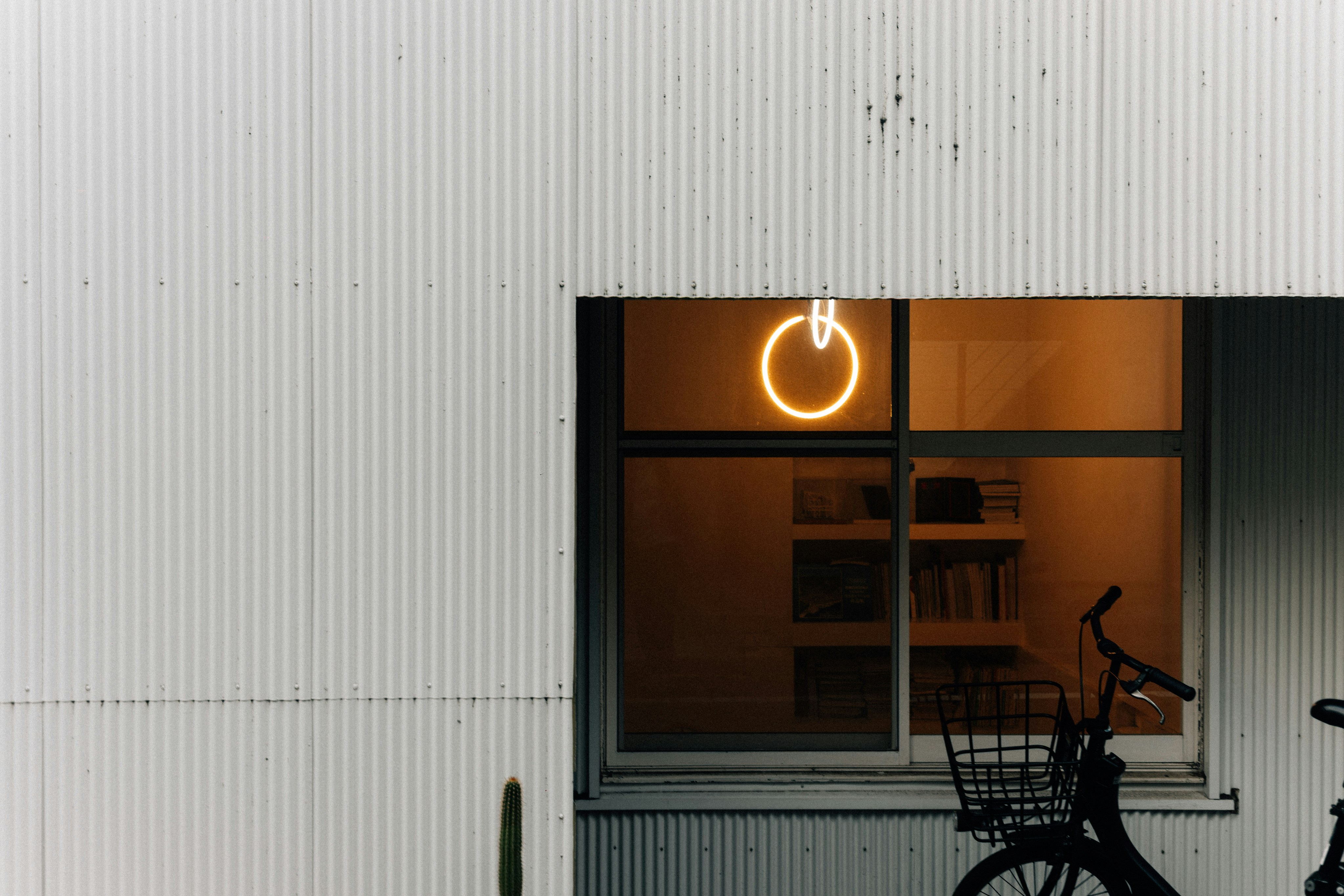Neon power button sign glows in a window at night.