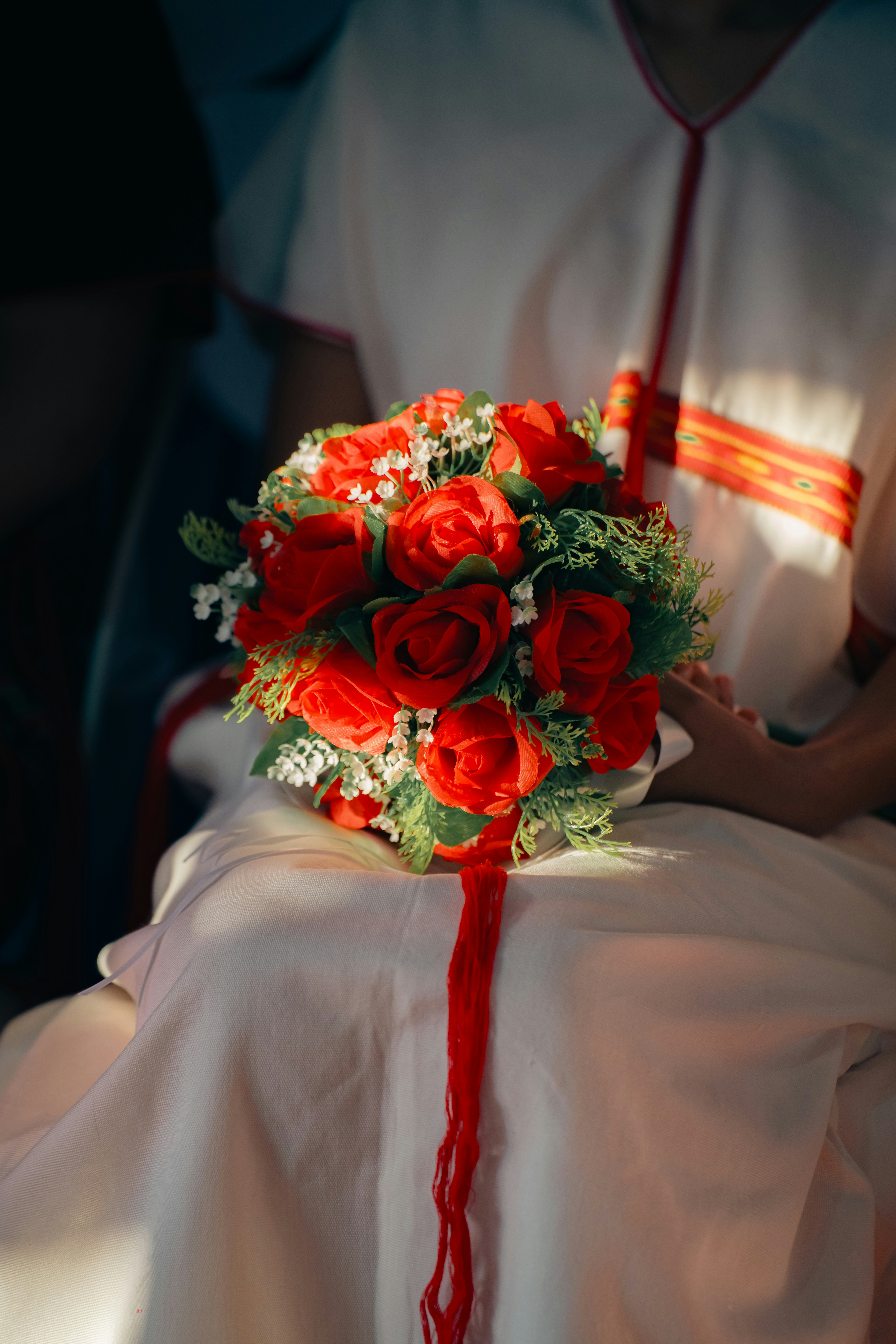 A bride holds a bouquet of red roses.