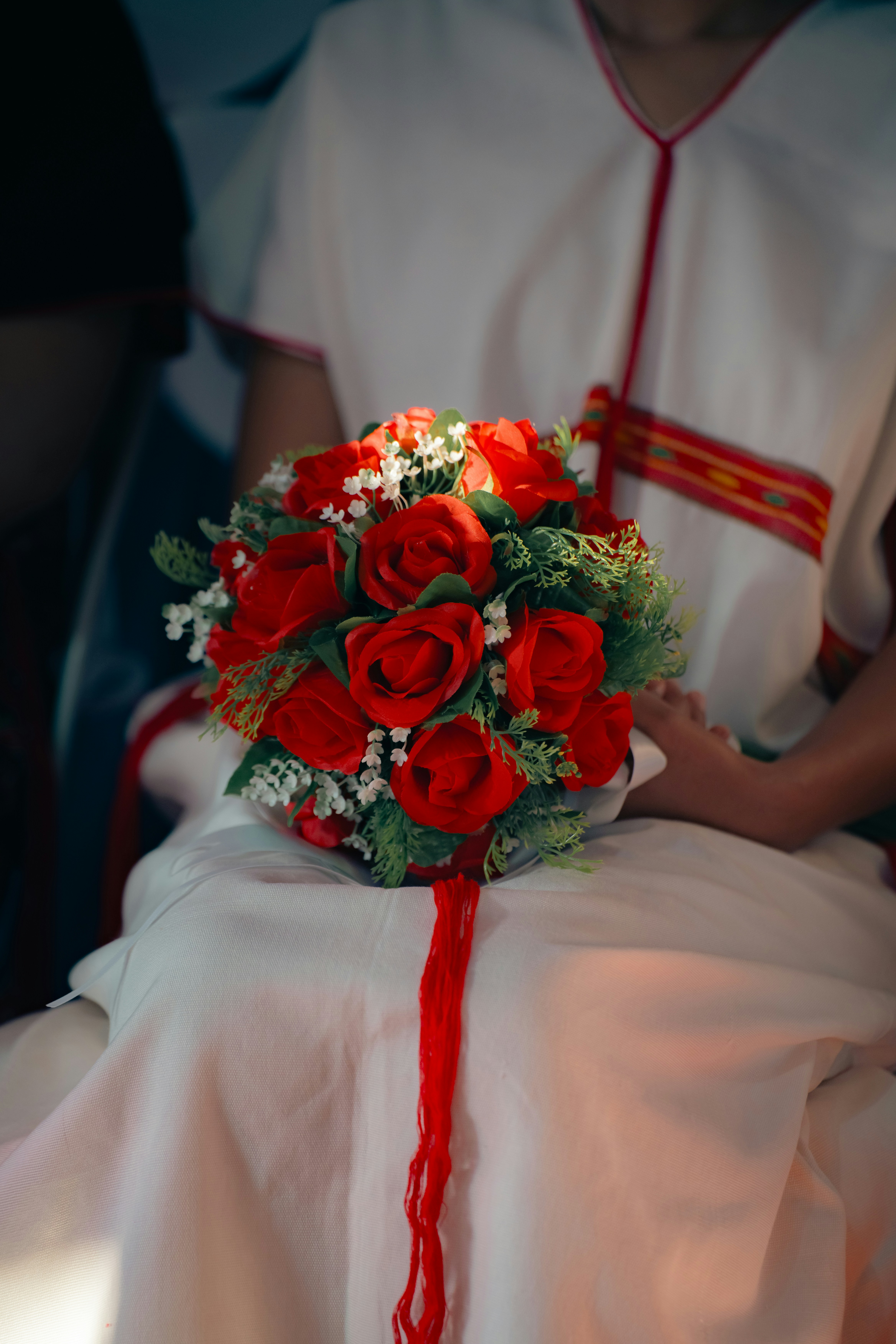 Red roses bouquet held by a person in white