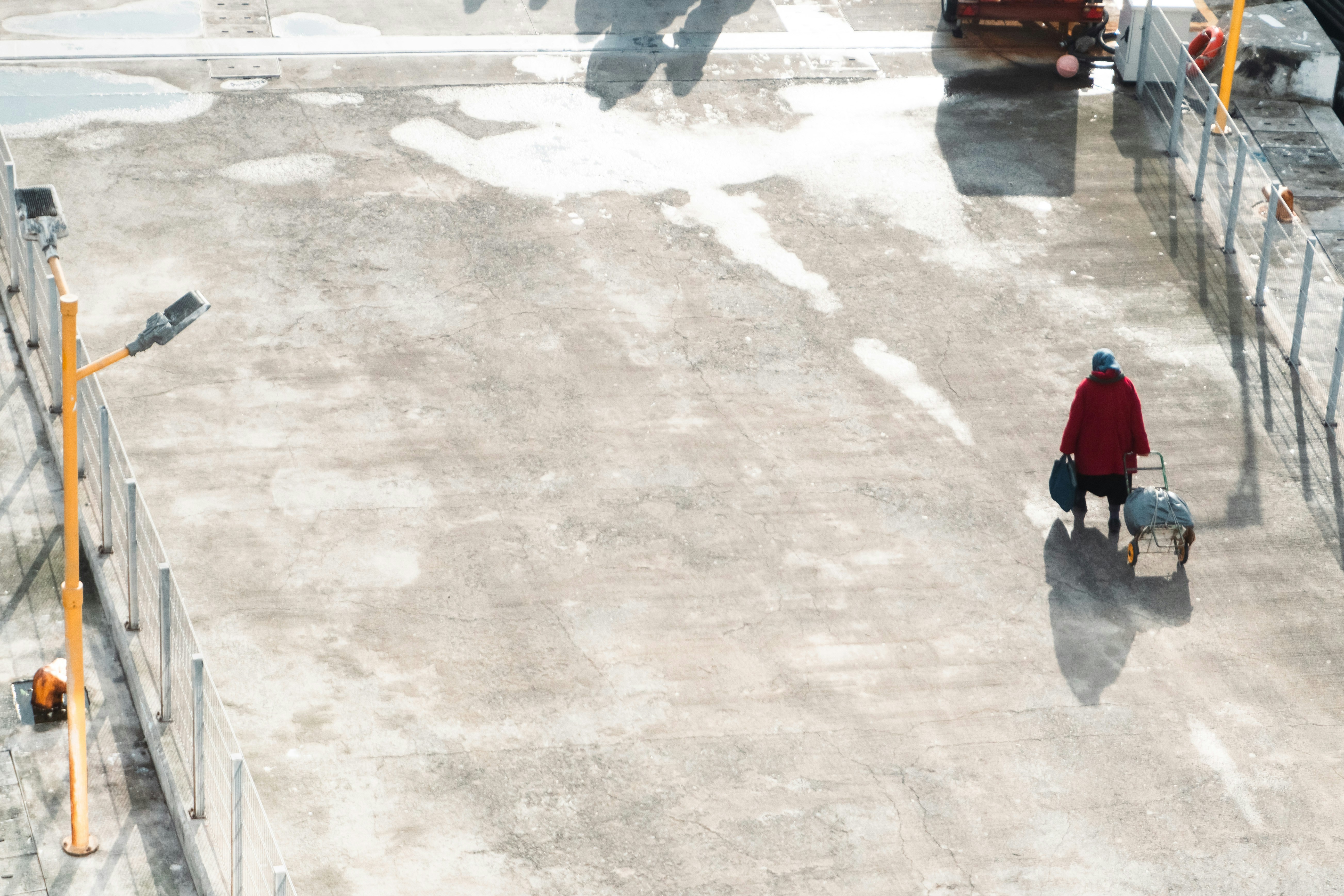 Woman with luggage walking on a wet pavement.