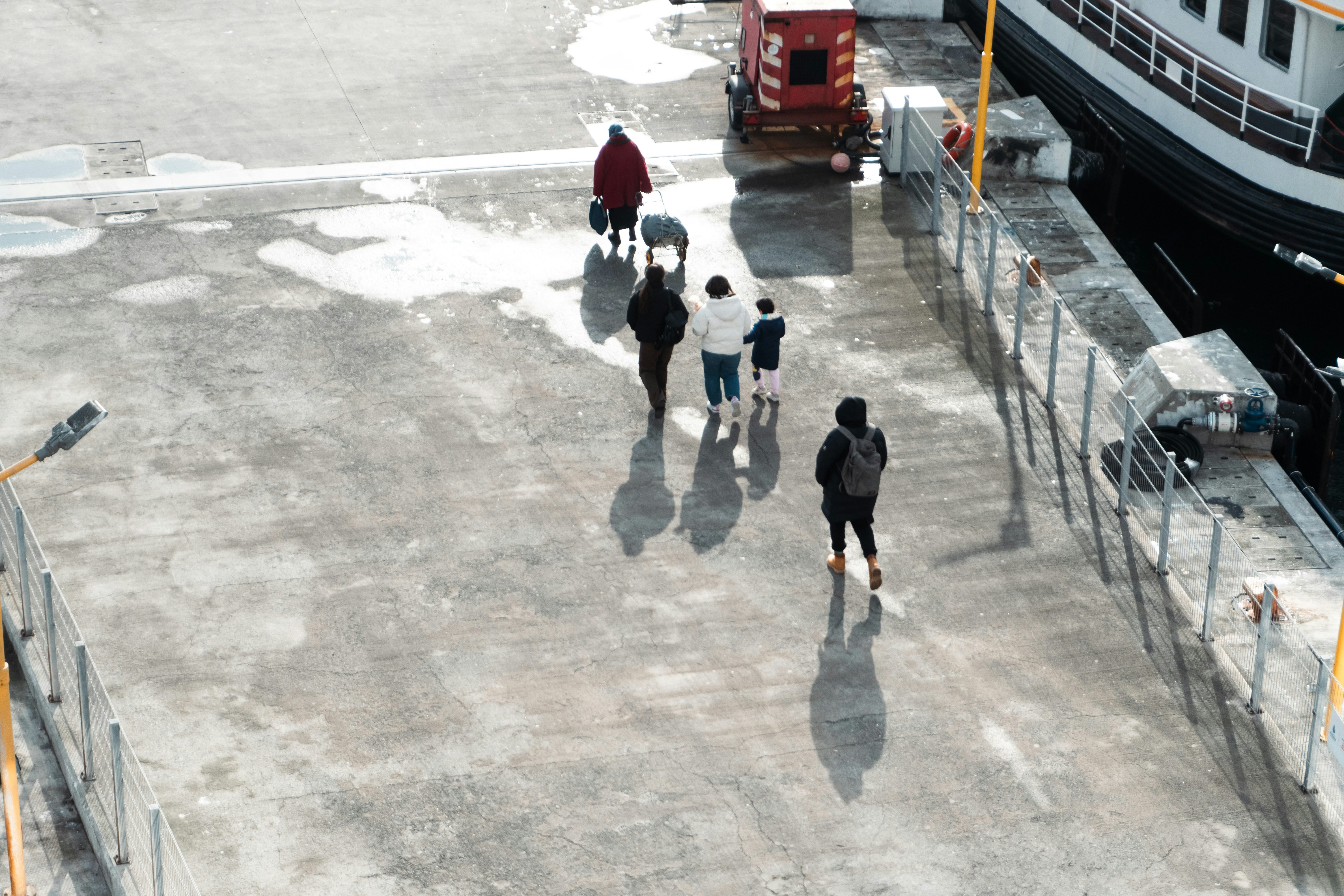 People walking on a concrete dock near a boat.