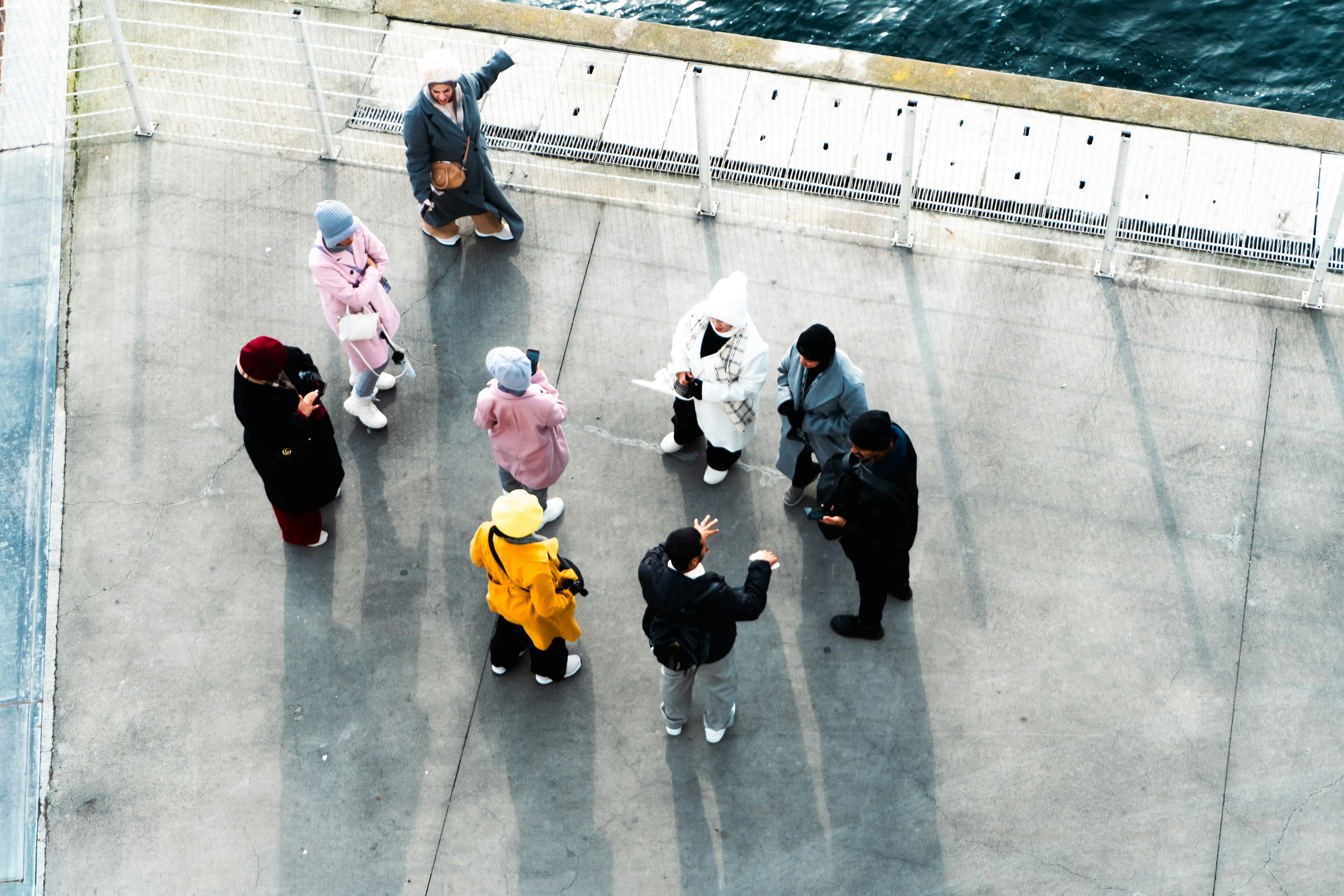 Group of people gathered on a concrete surface near water.