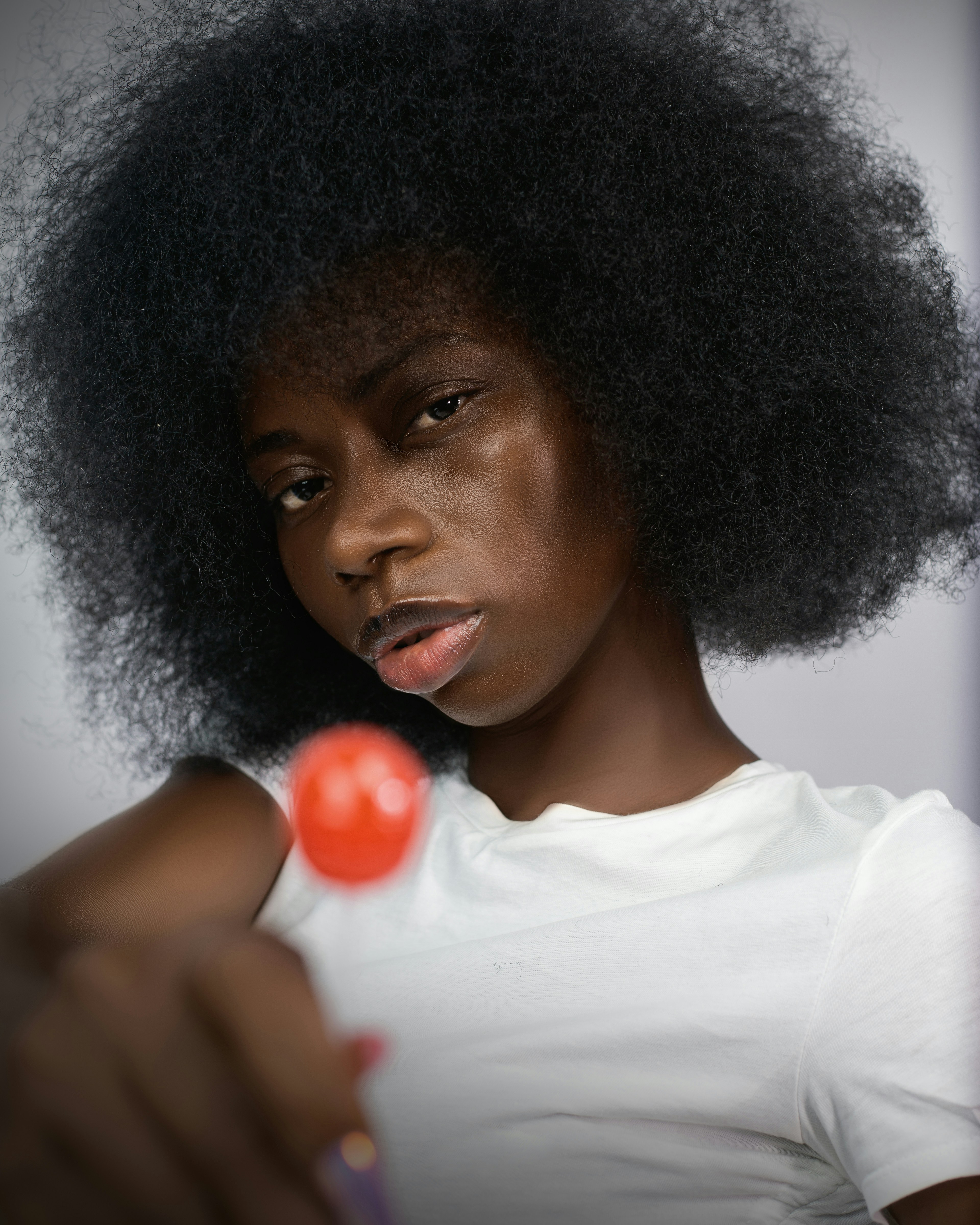 Junge Frau mit Afro, die einen Lutscher hält