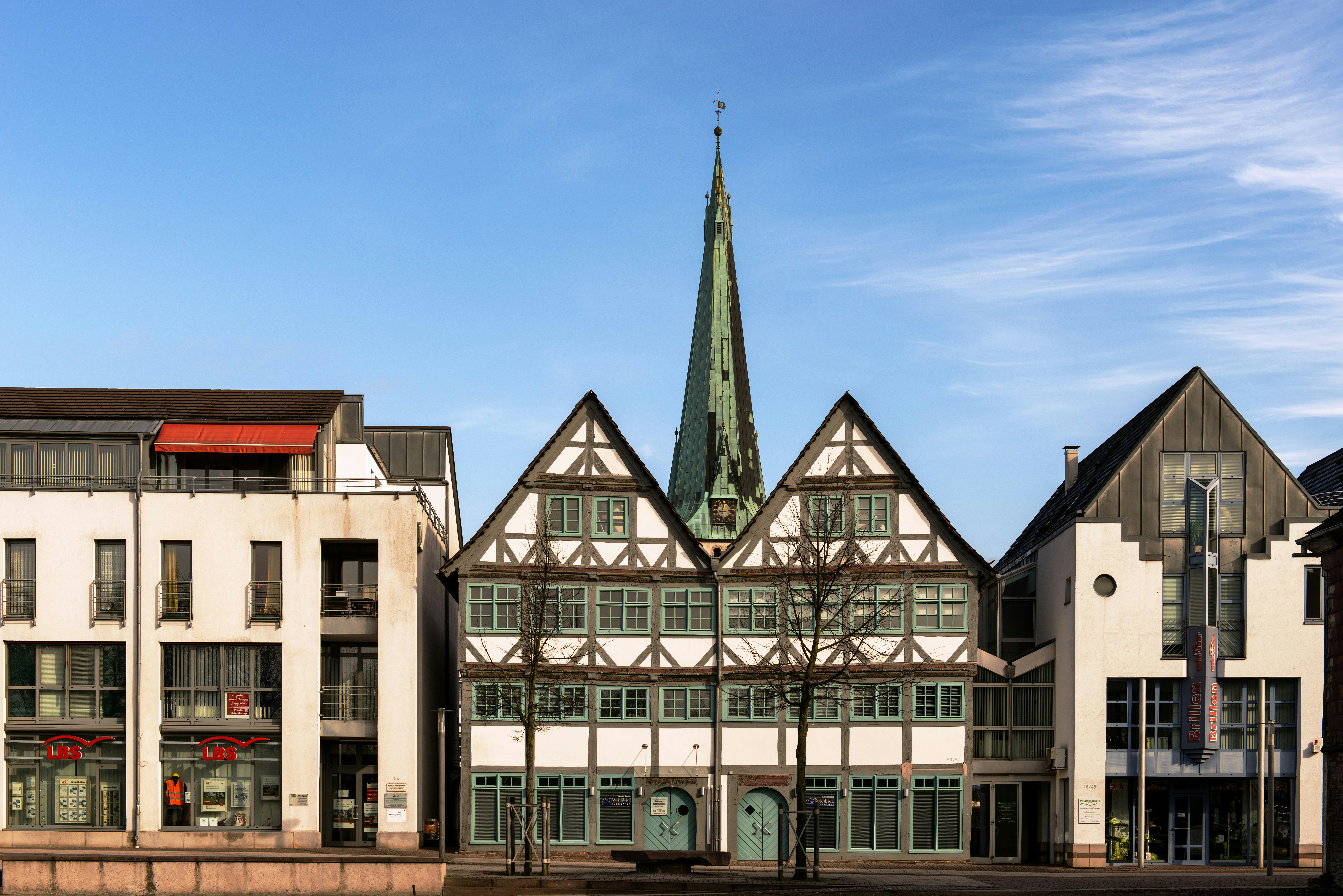 Half-timbered buildings with a church steeple behind them.