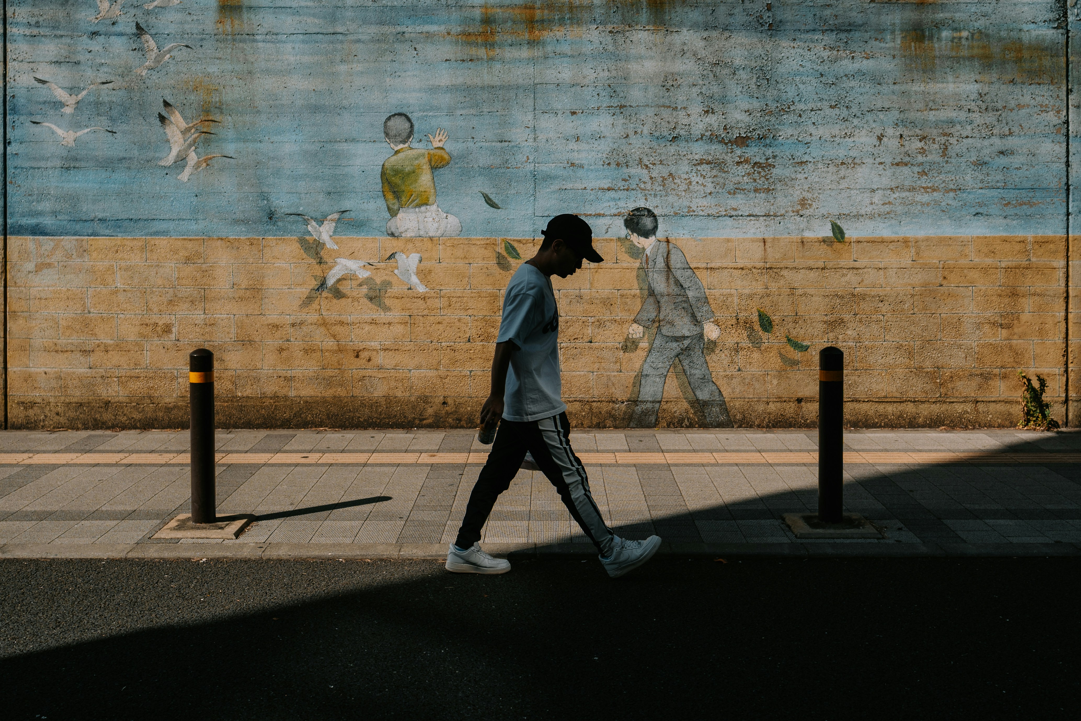 Man walks past mural on a sunny day