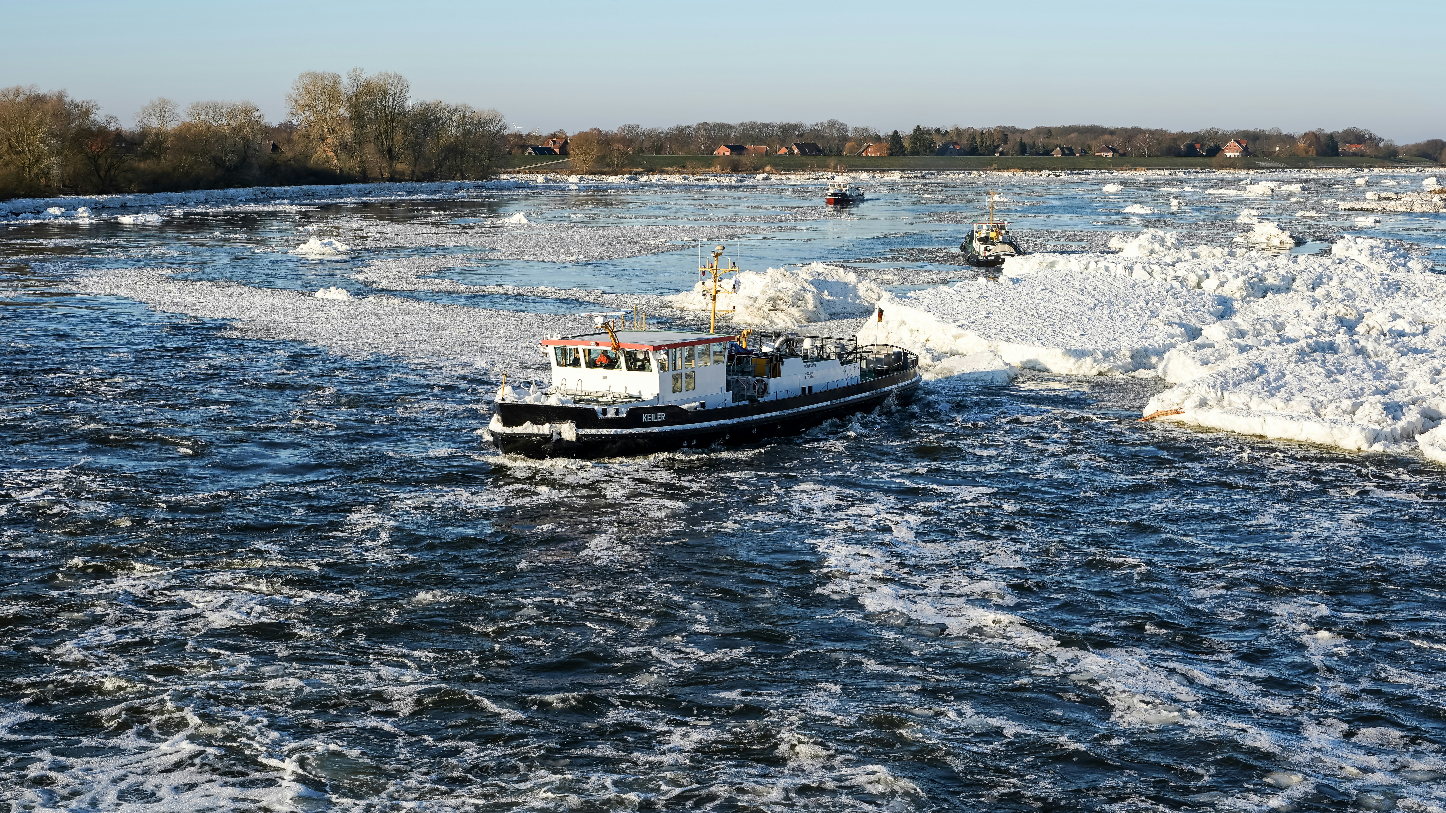 A boat navigates through icy river water.