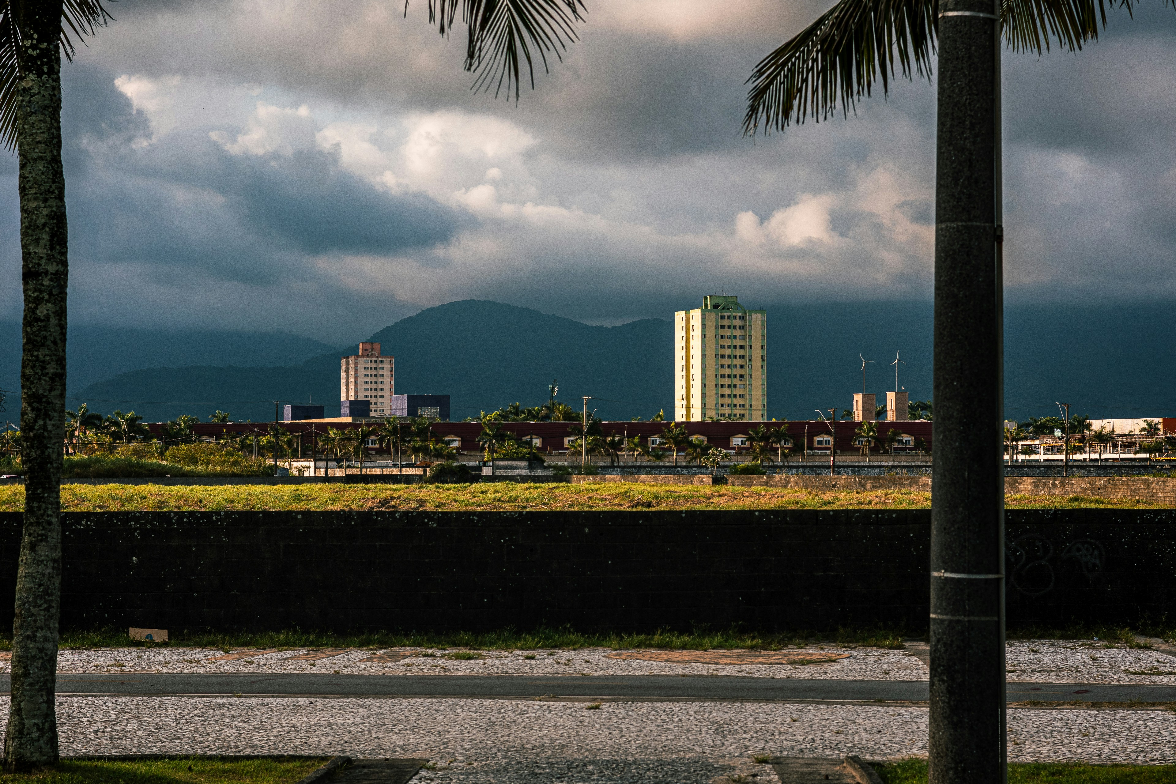 De hauts immeubles se dressent contre un ciel nuageux près des montagnes.
