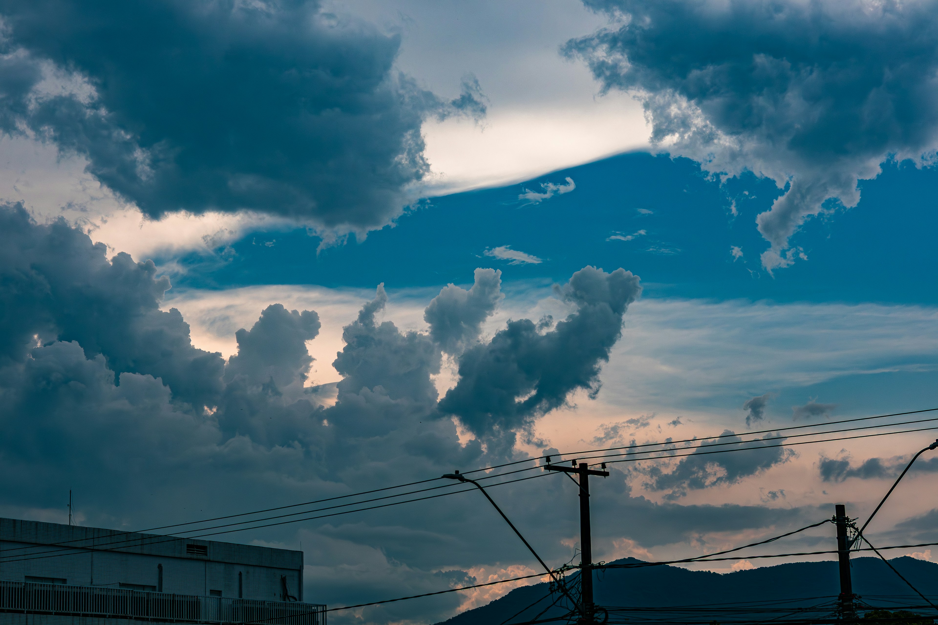Dramatic clouds fill the sky above mountains and beyond mountains.
