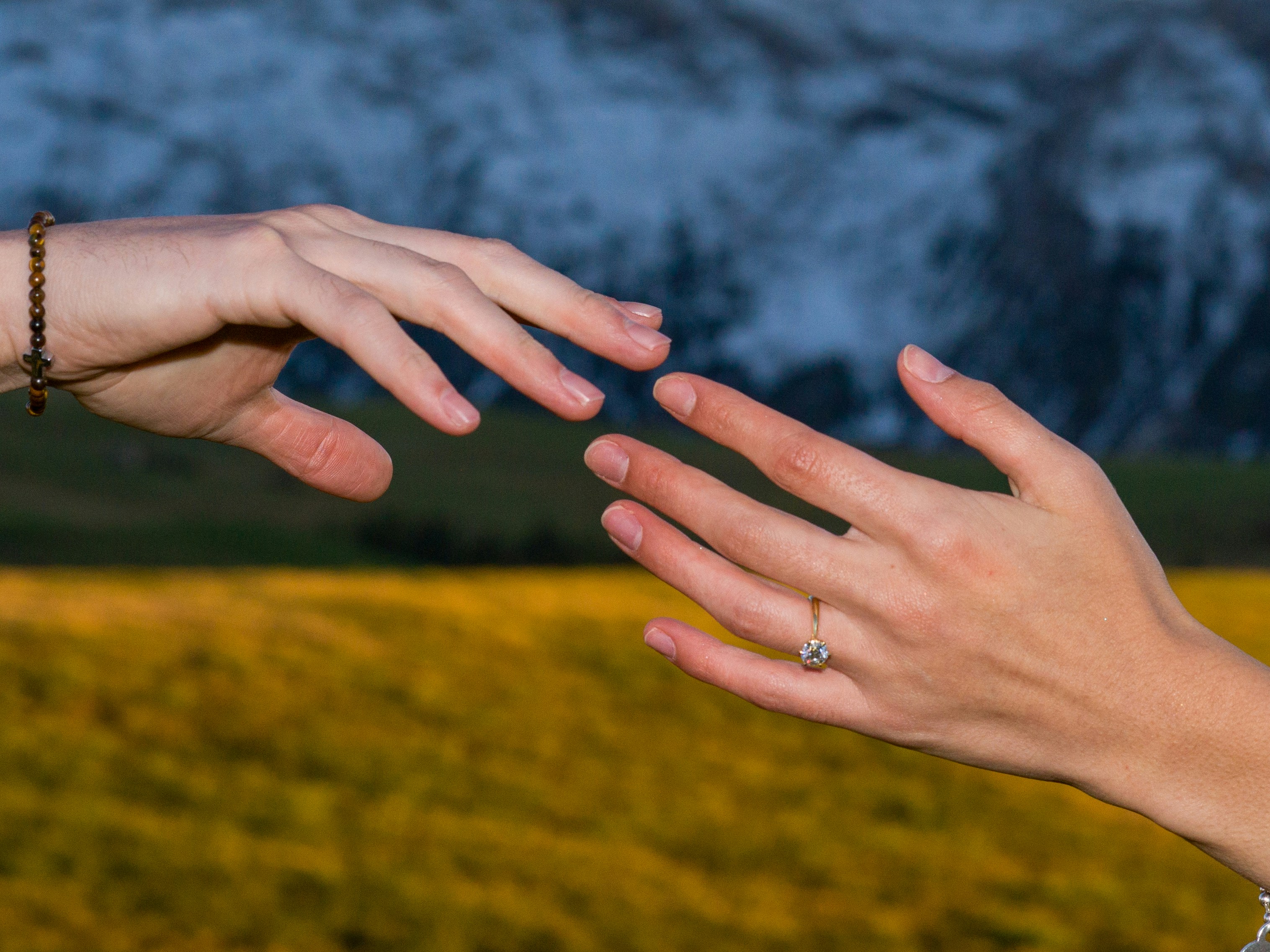Dos manos extendidas una hacia la otra con montañas detrás
