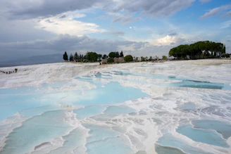 Terraced white travertine pools with blue water and trees