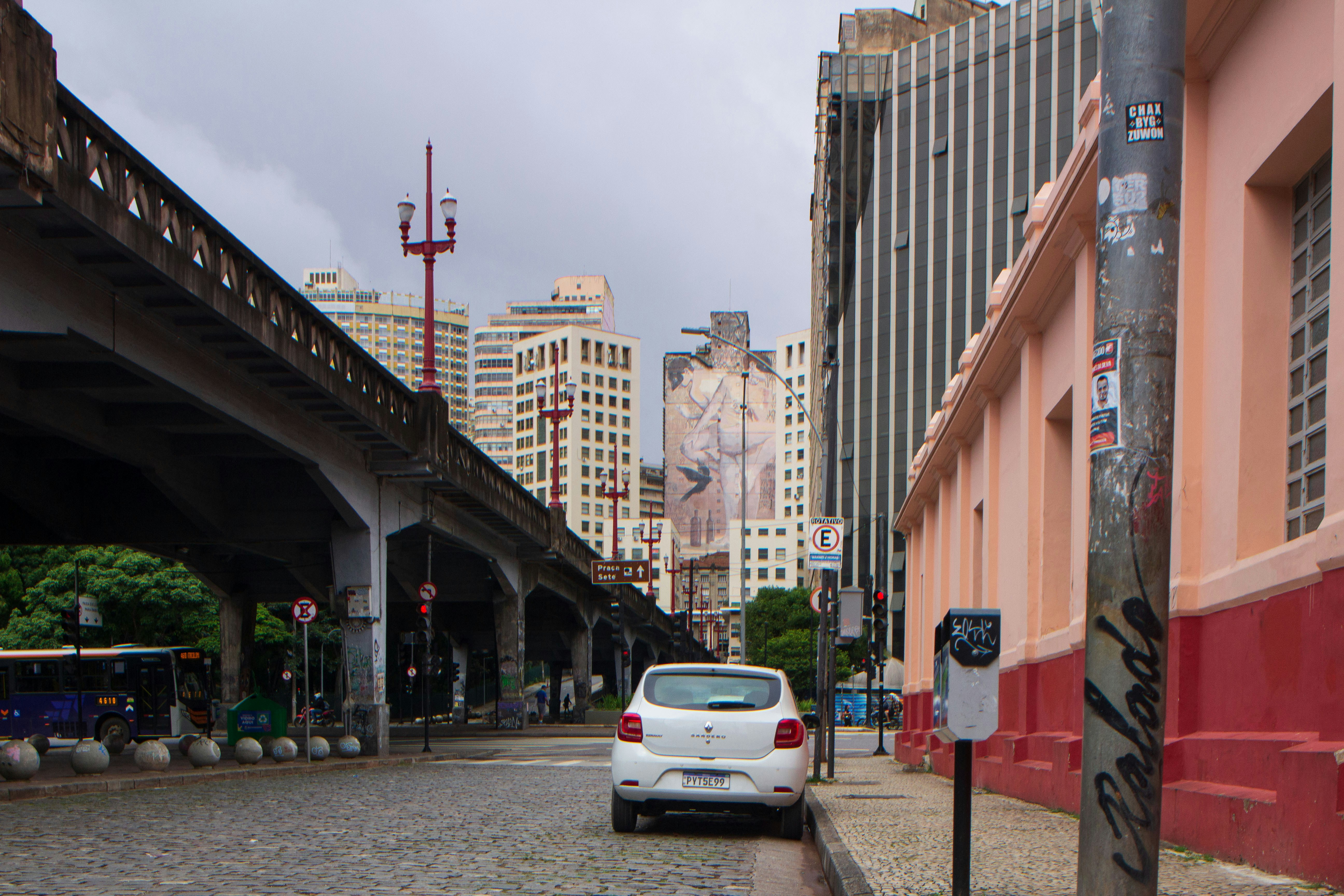 A white car parked on a city street with buildings.