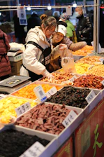 Vendors sell dried fruits and nuts at a market.
