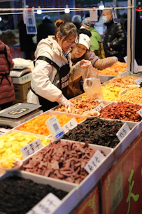 Vendors sell dried fruits and nuts at a market.