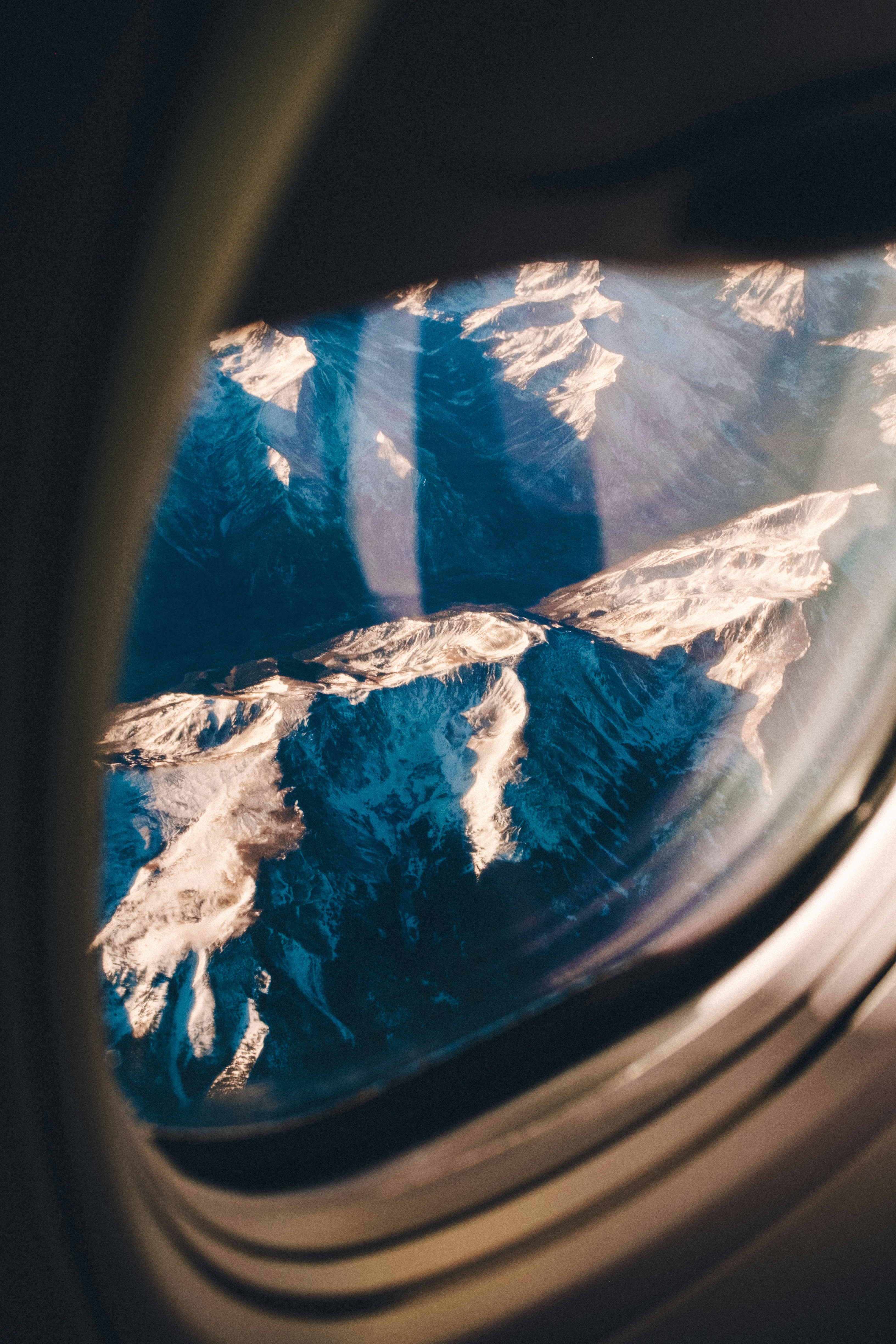 Snow-capped mountains seen through an airplane window.