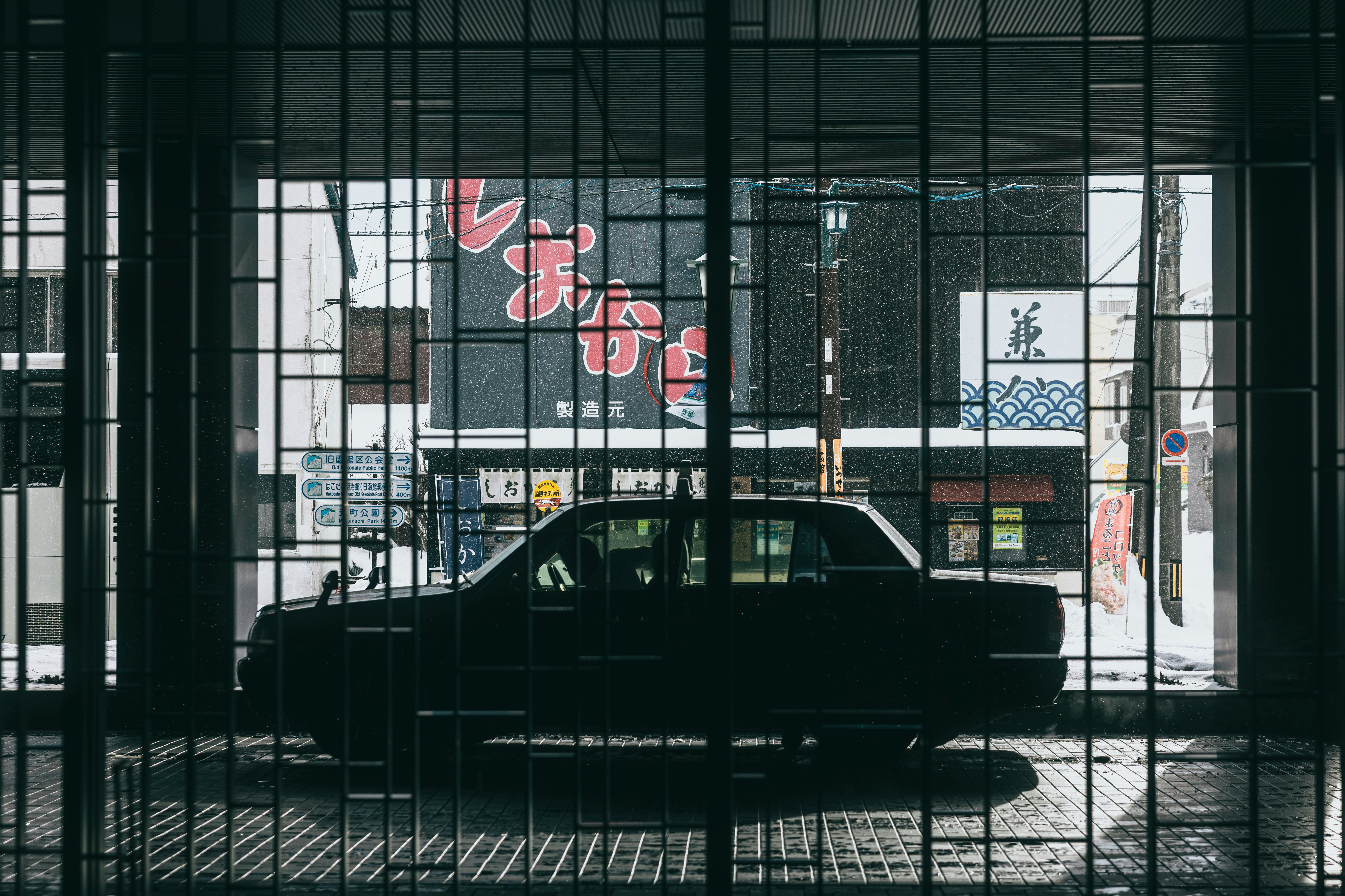 Silhouette of a car behind metal bars at night.