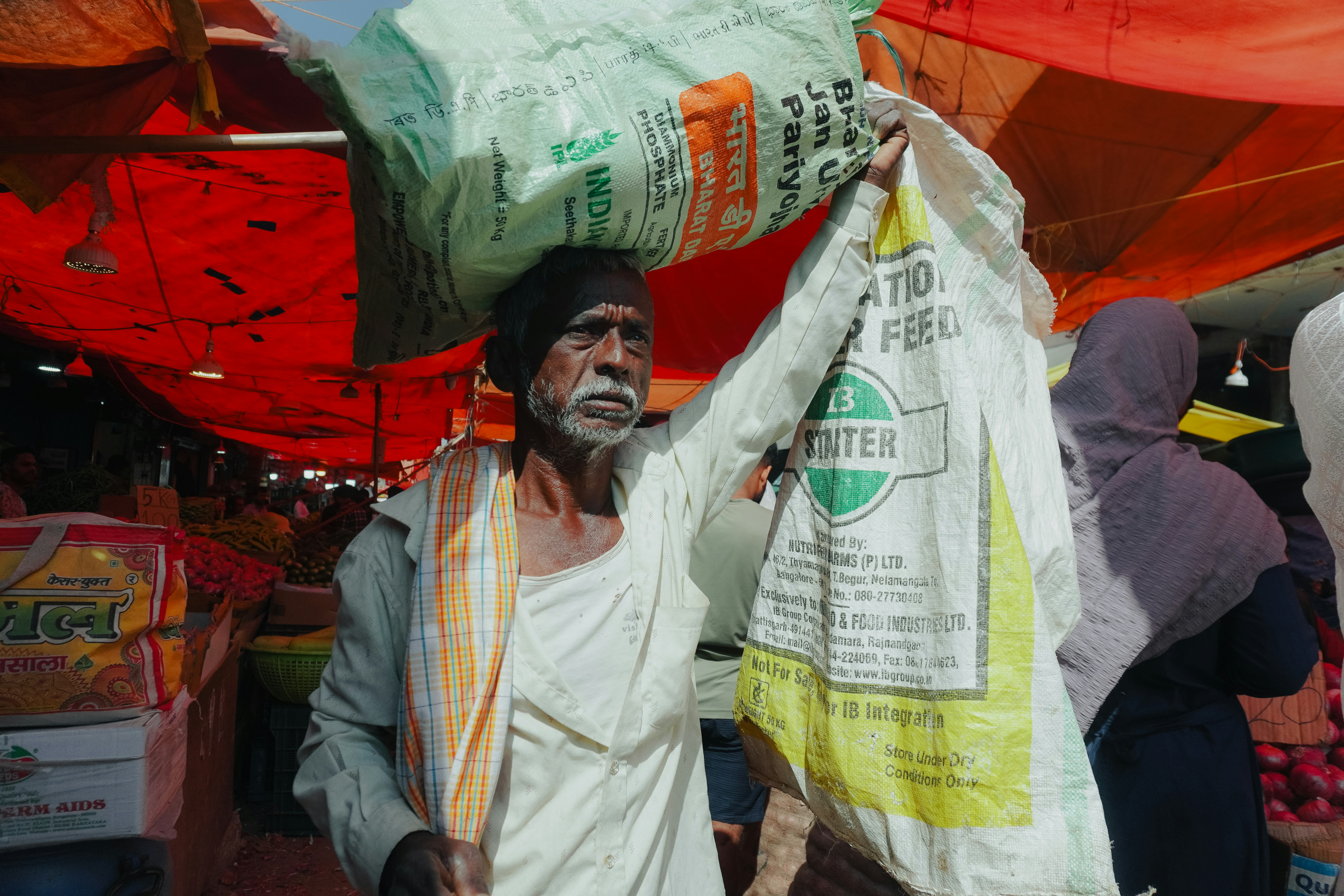 Elderly man carries heavy bags on his head