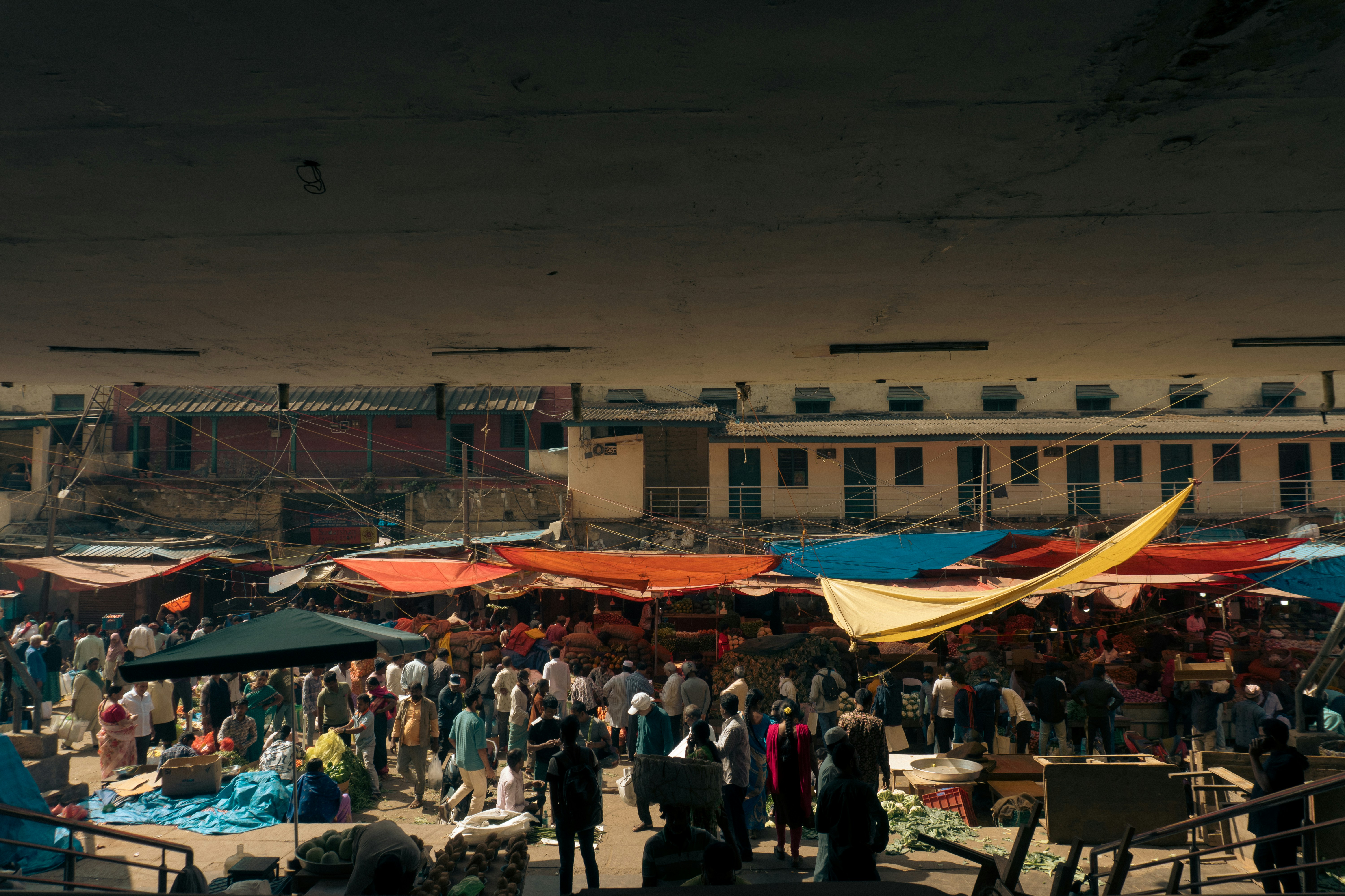 Crowded outdoor market with colorful tents and stalls.