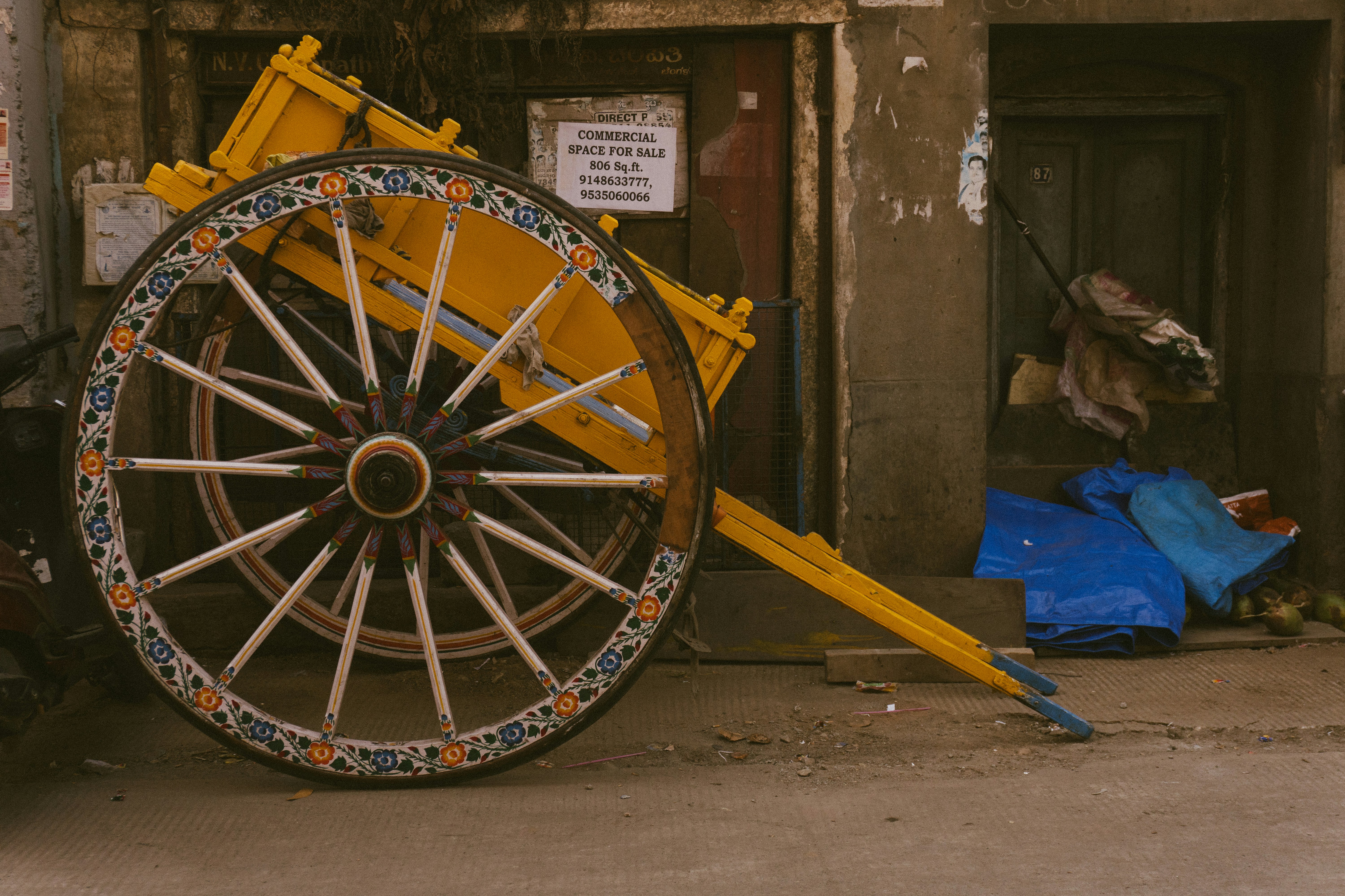 A yellow cart with a decorative spoked wheel