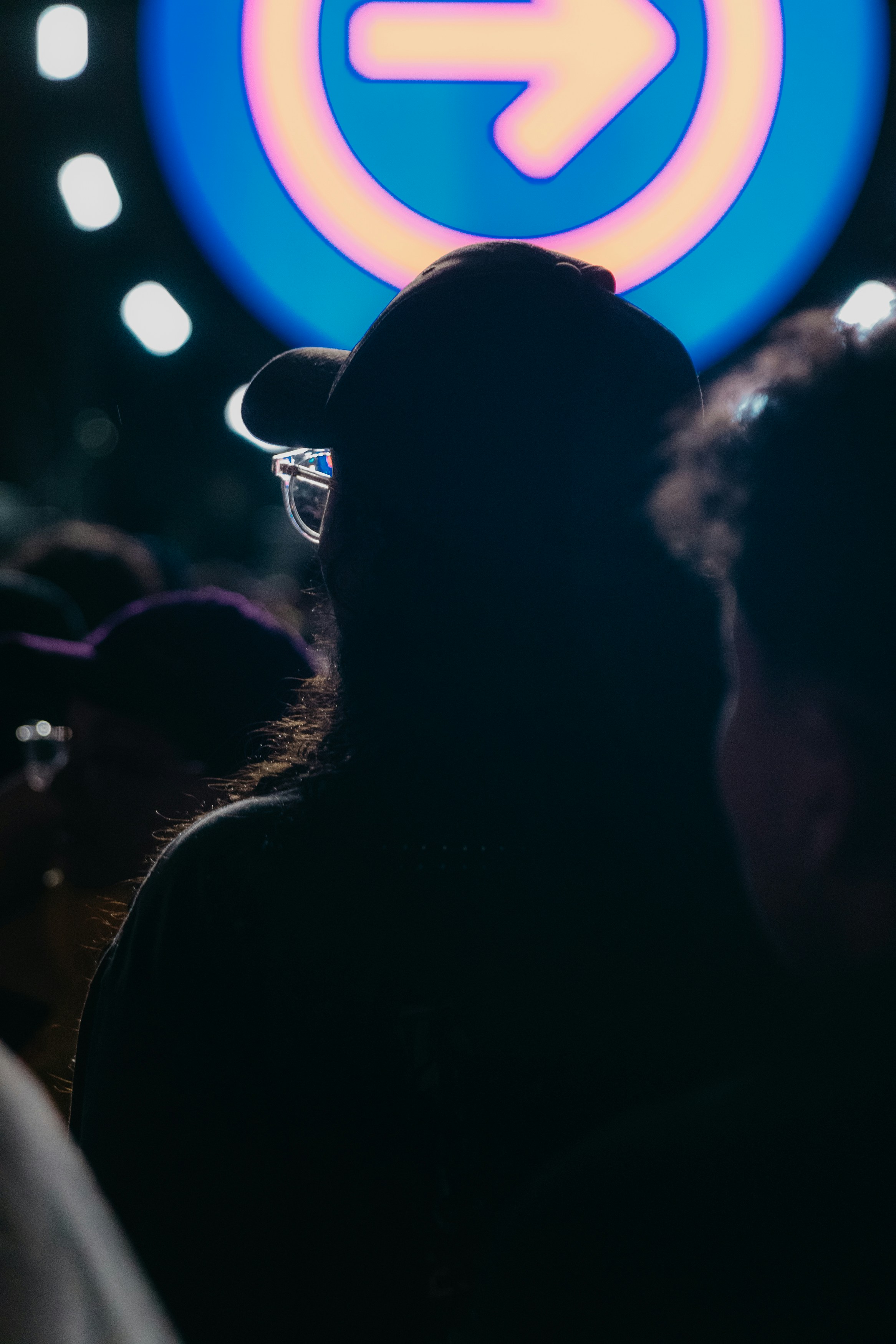 Silhouette of people at a concert with neon arrow sign