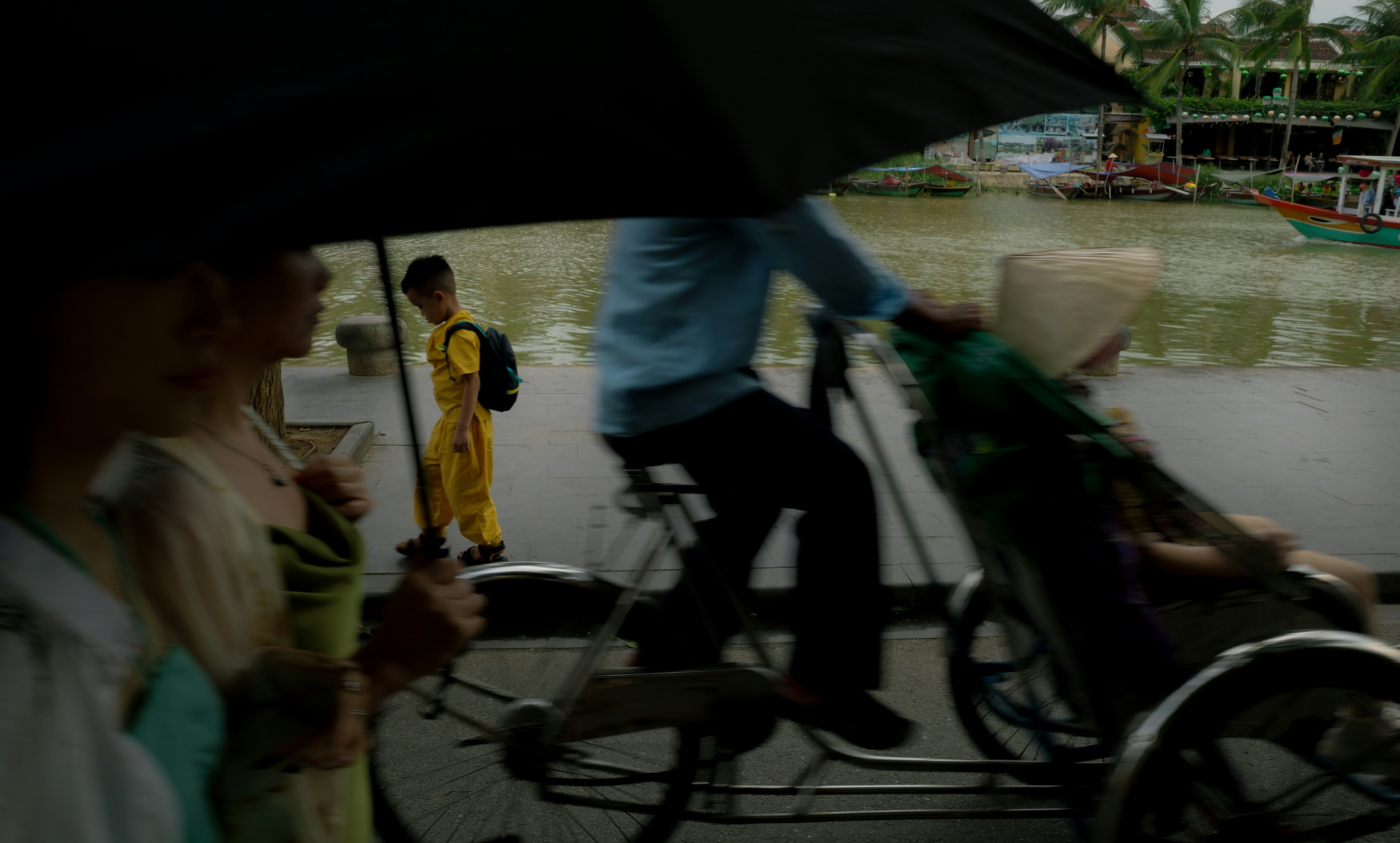 People with umbrella near river with boat