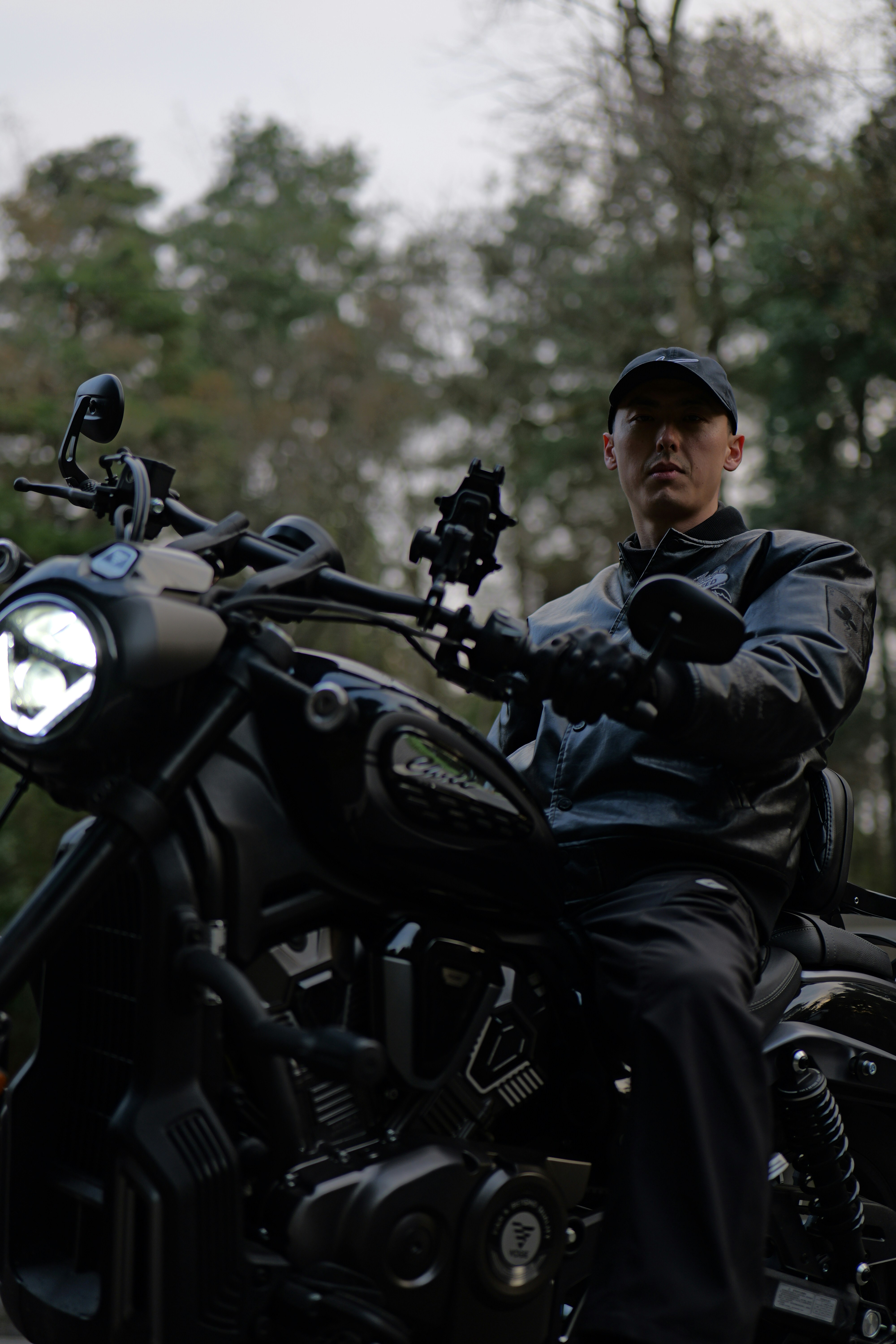 Man in leather jacket riding a black motorcycle