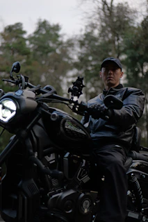 Man in leather jacket riding a black motorcycle