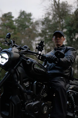 Man in leather jacket riding a black motorcycle