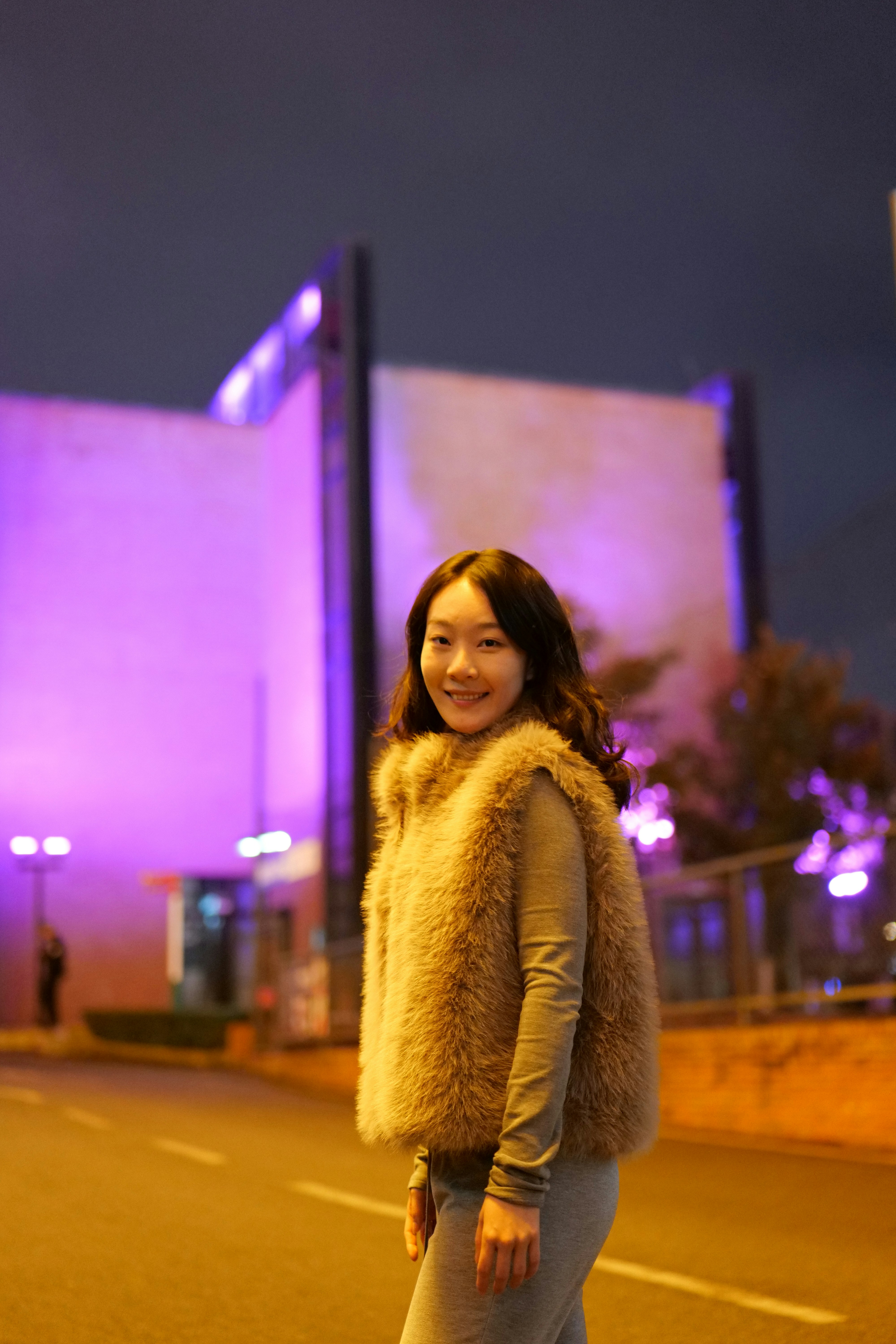 Young woman smiling in front of purple lit building