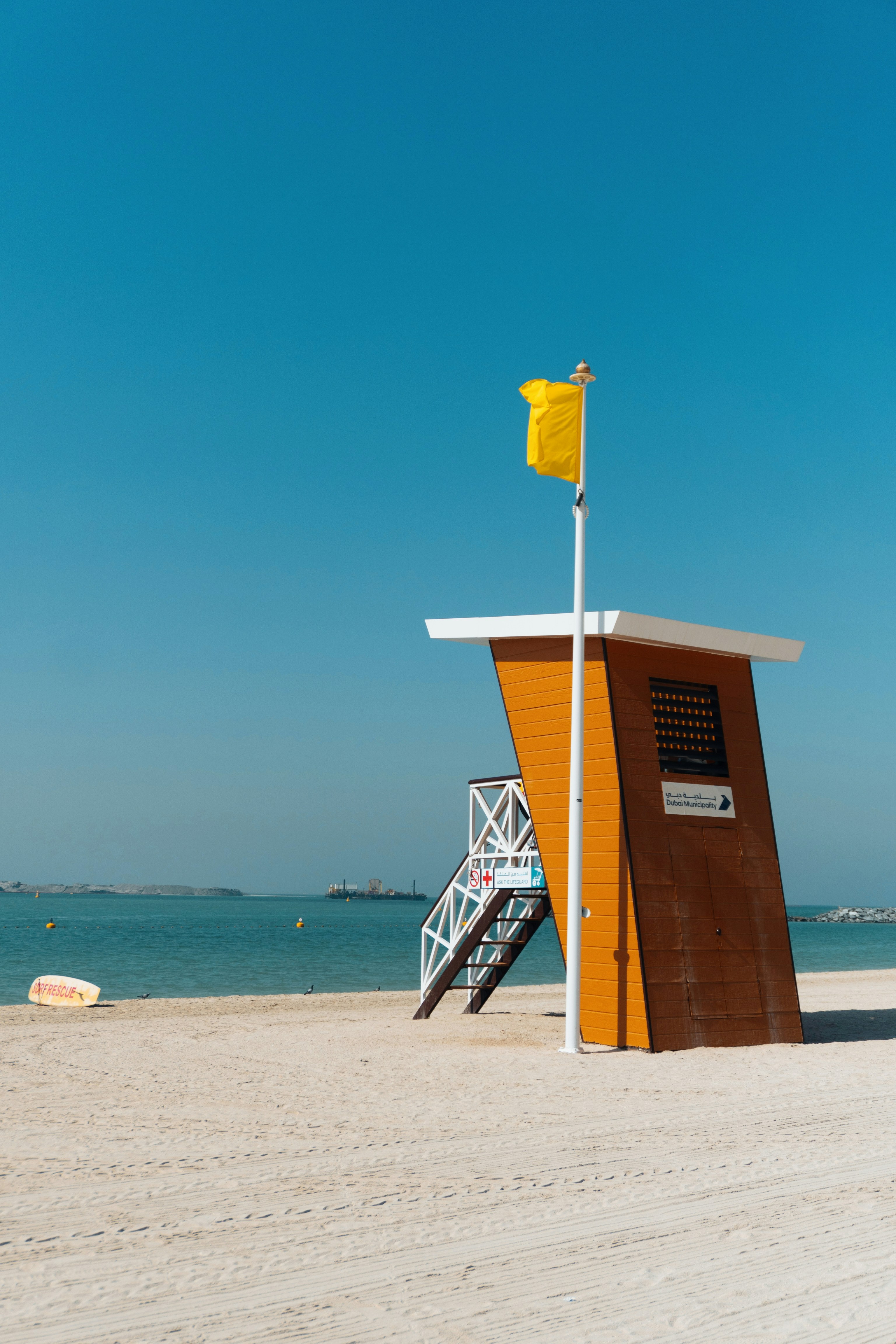 Torre arancione dei bagnini con bandiera gialla sulla spiaggia.
