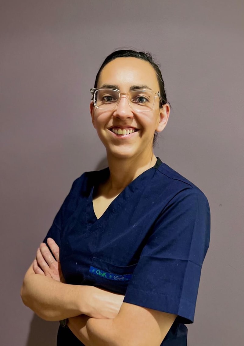 Maria Delgado, senior caregiver, smiling in scrubs