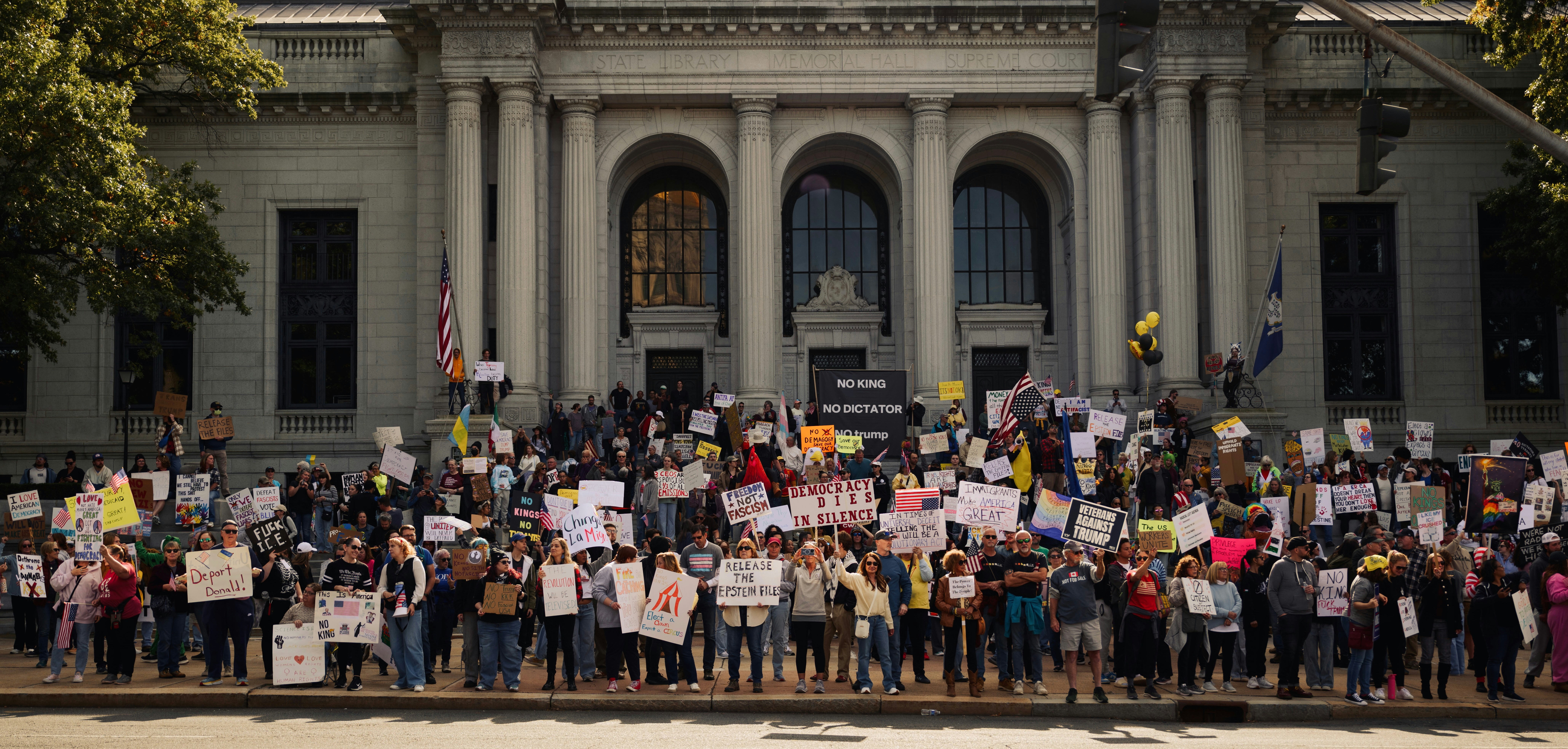 Protesters with signs gather on building steps