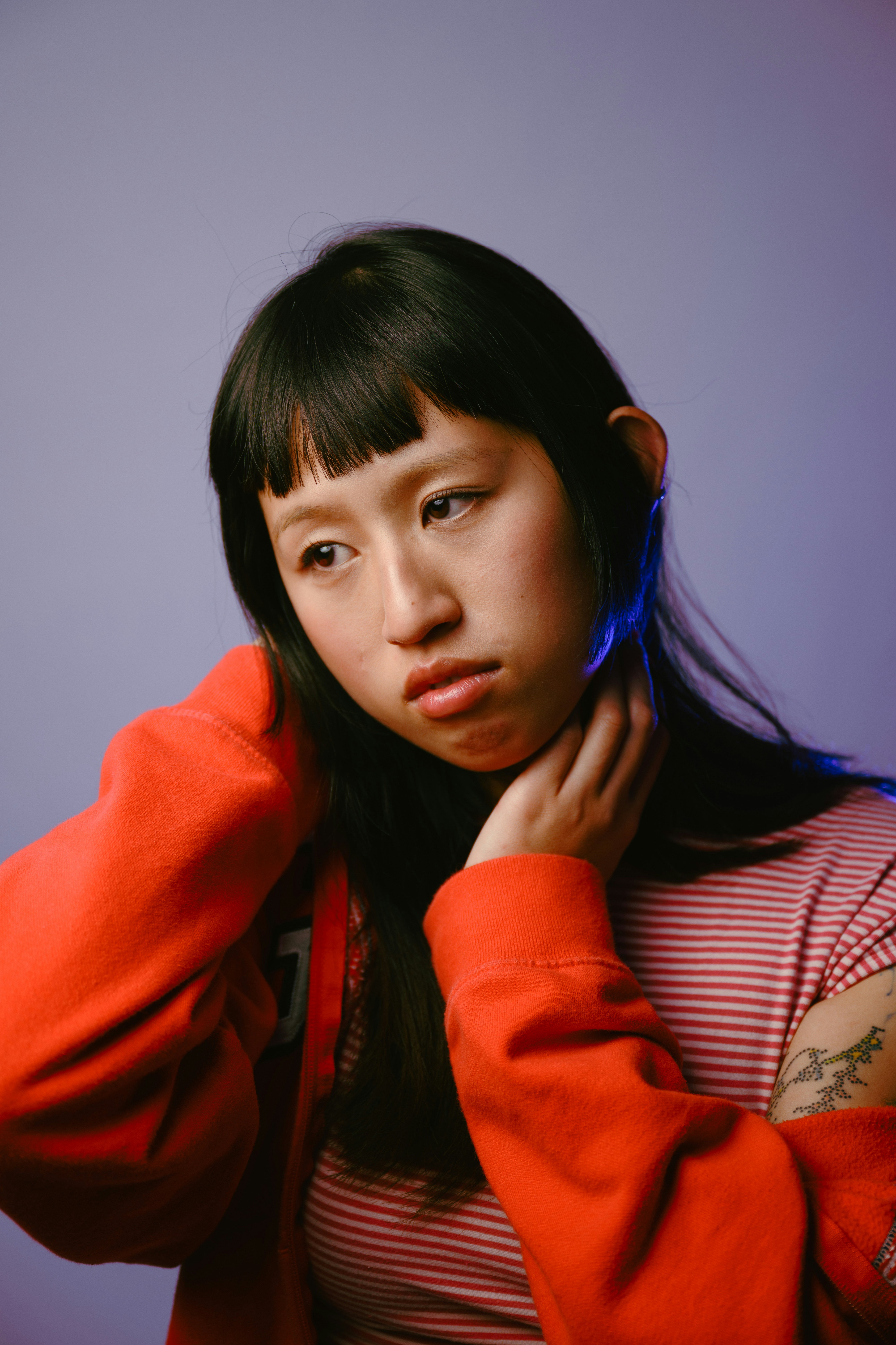 Young woman with dark hair and bangs, wearing red.