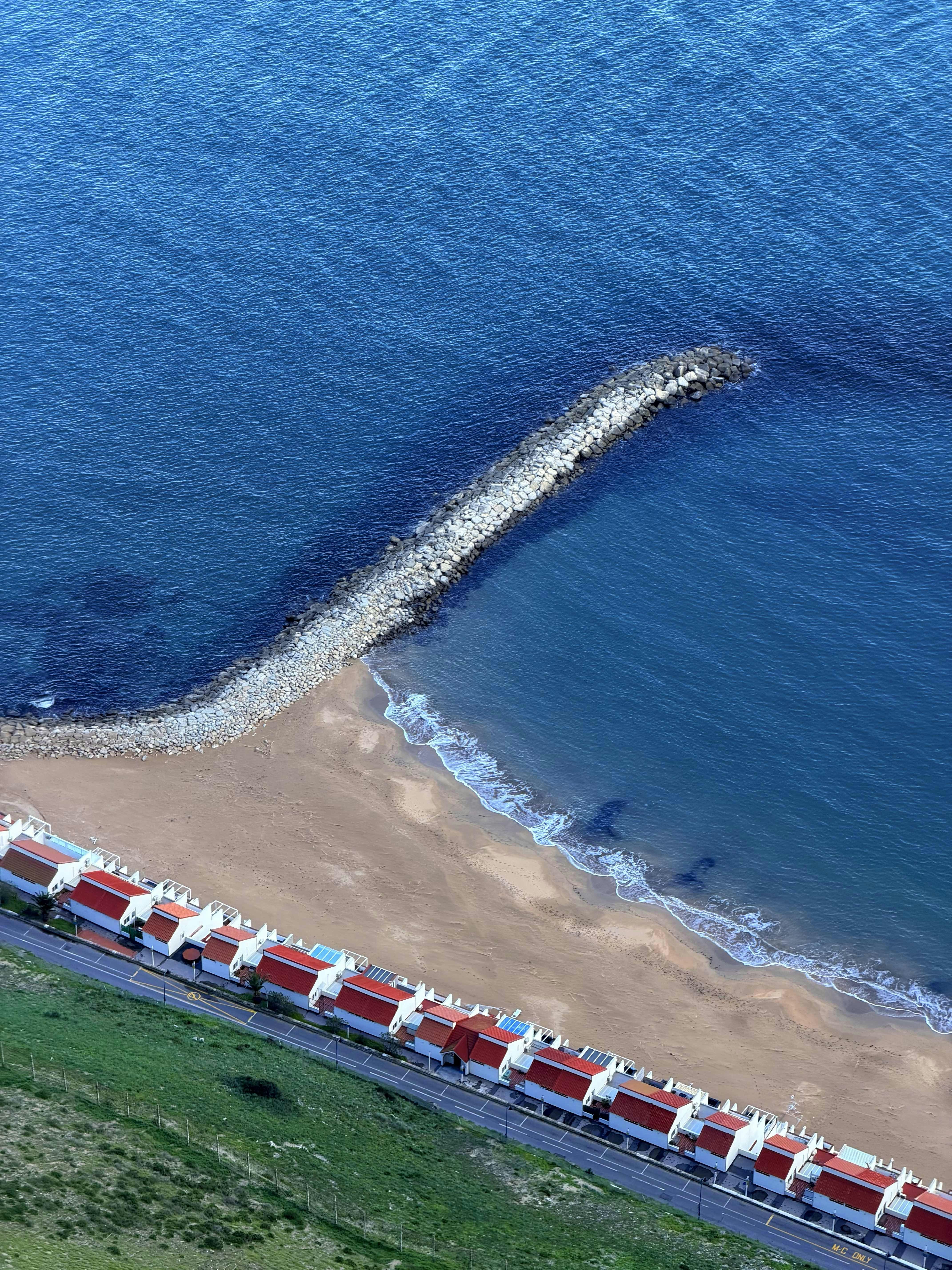 Row of houses by the ocean with a breakwater.
