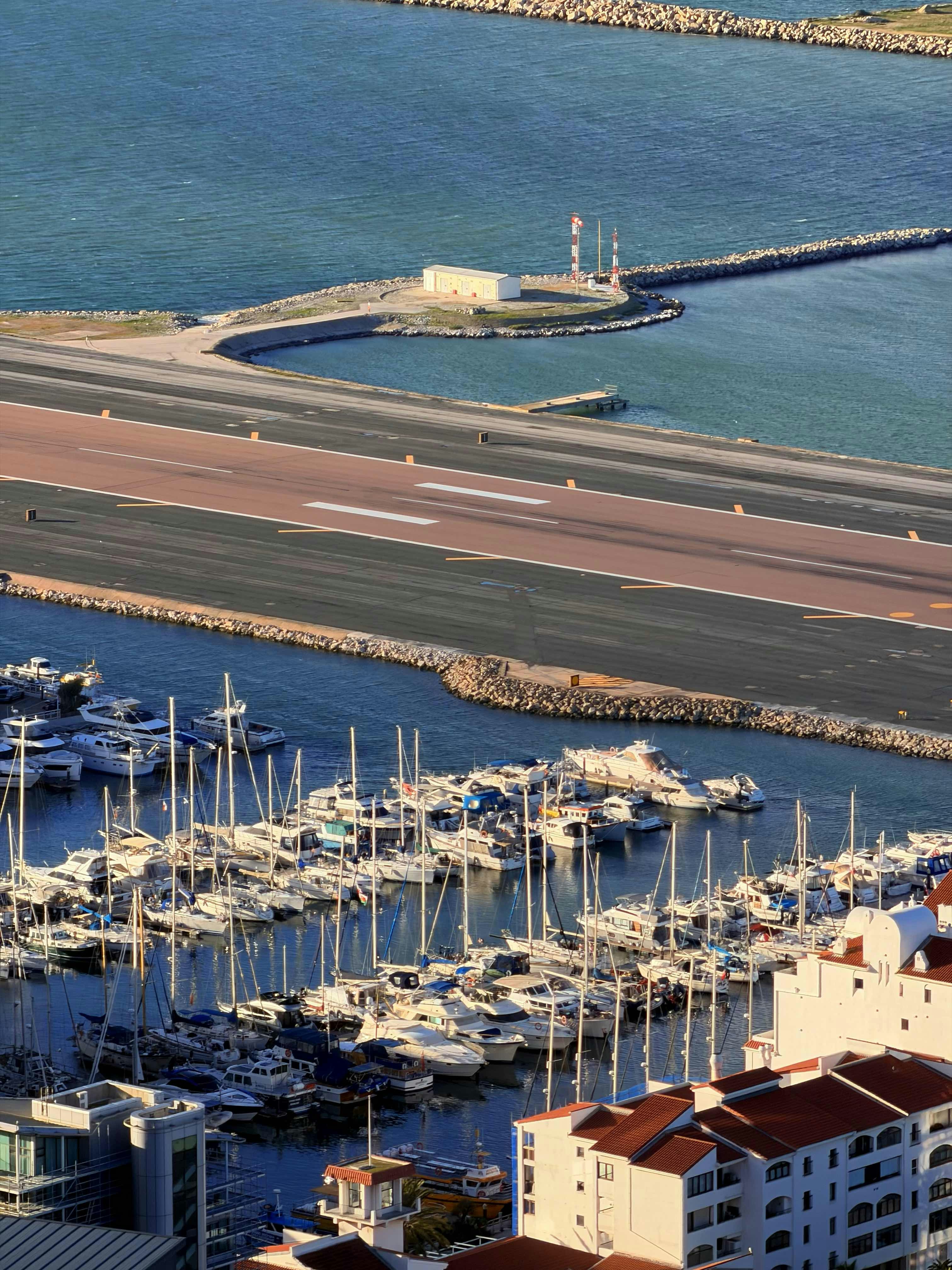 Boats docked in marina with airport runway nearby