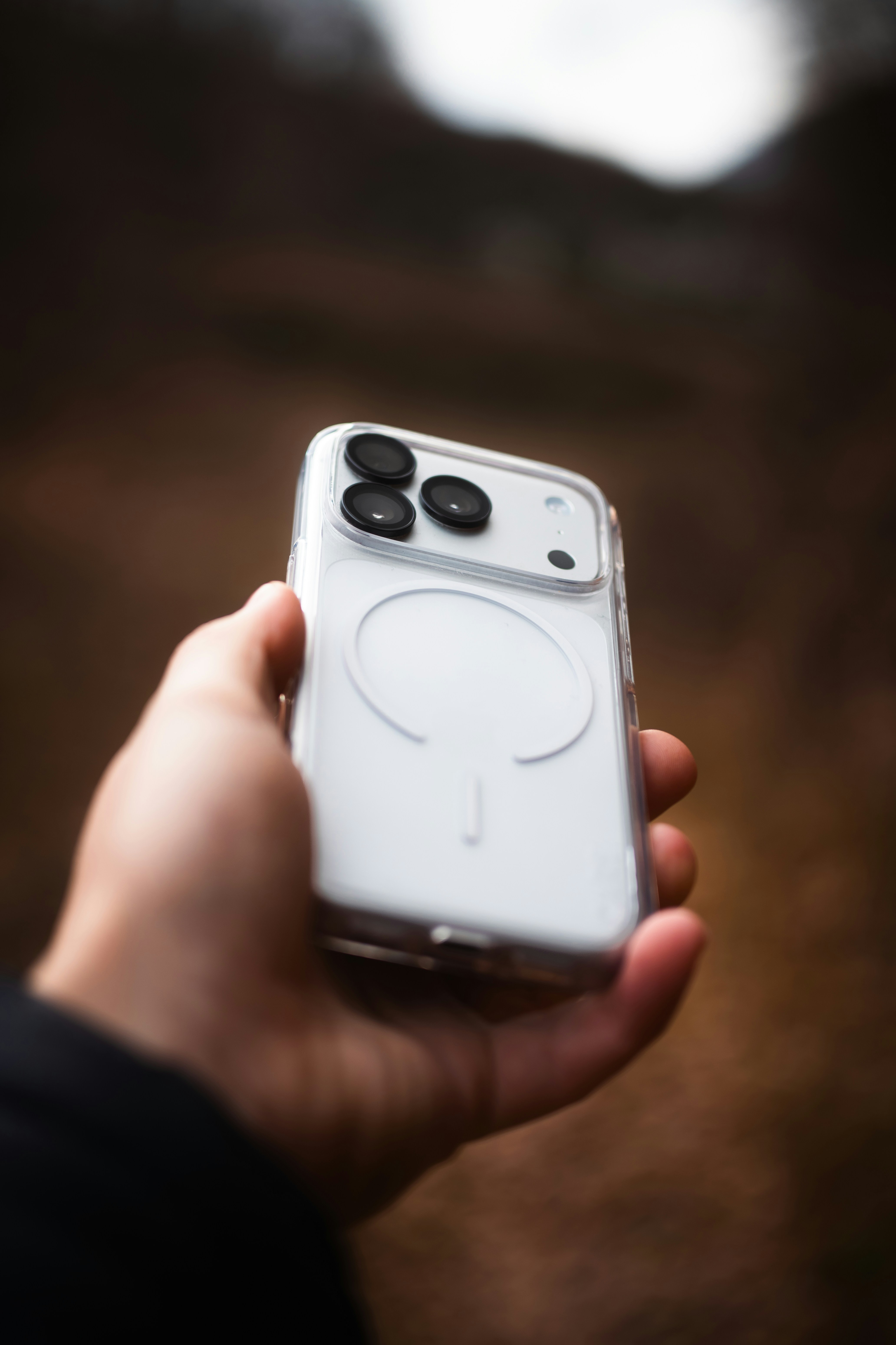 Hand holding a white smartphone in a clear case.