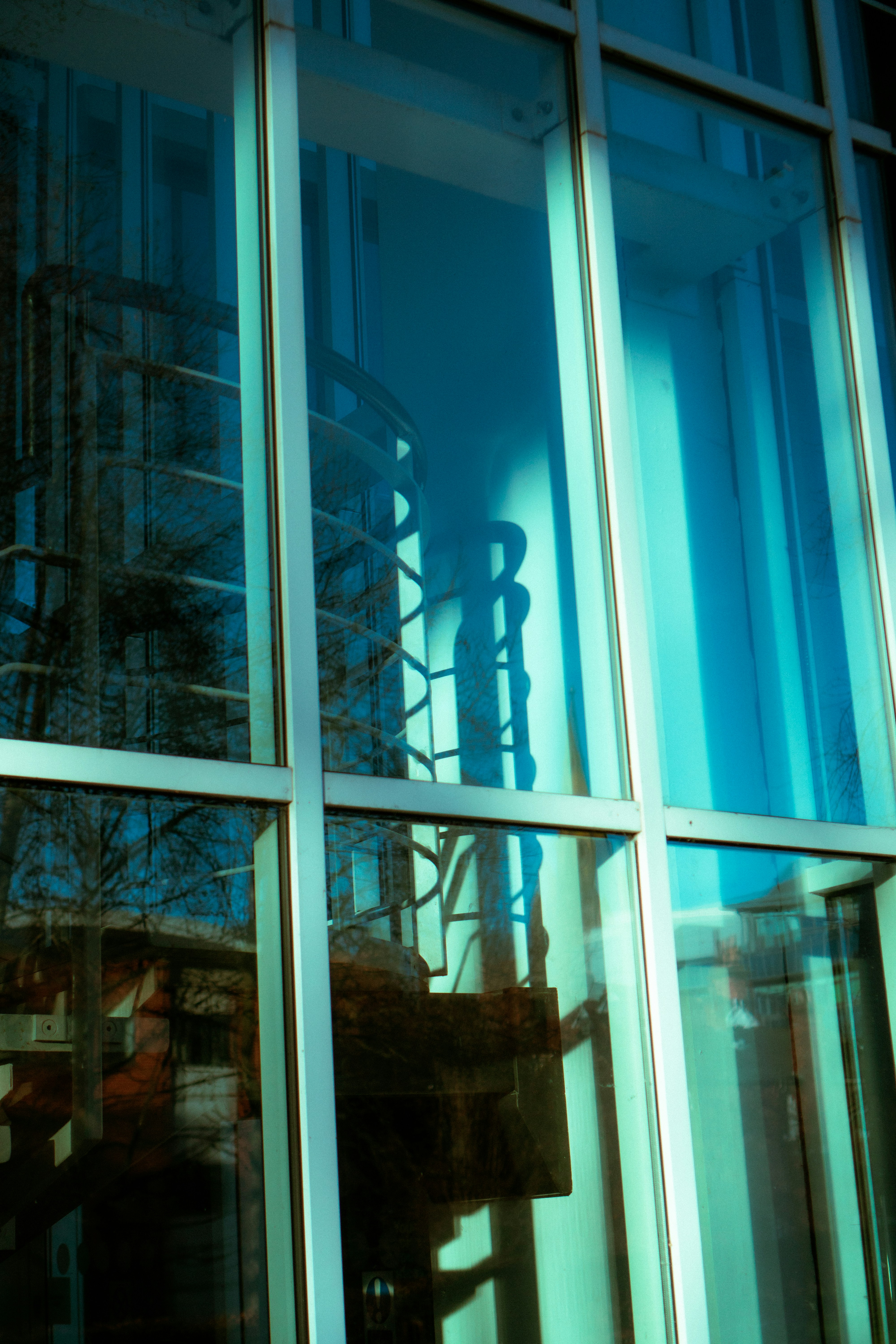 Spiral staircase reflected in blue glass building