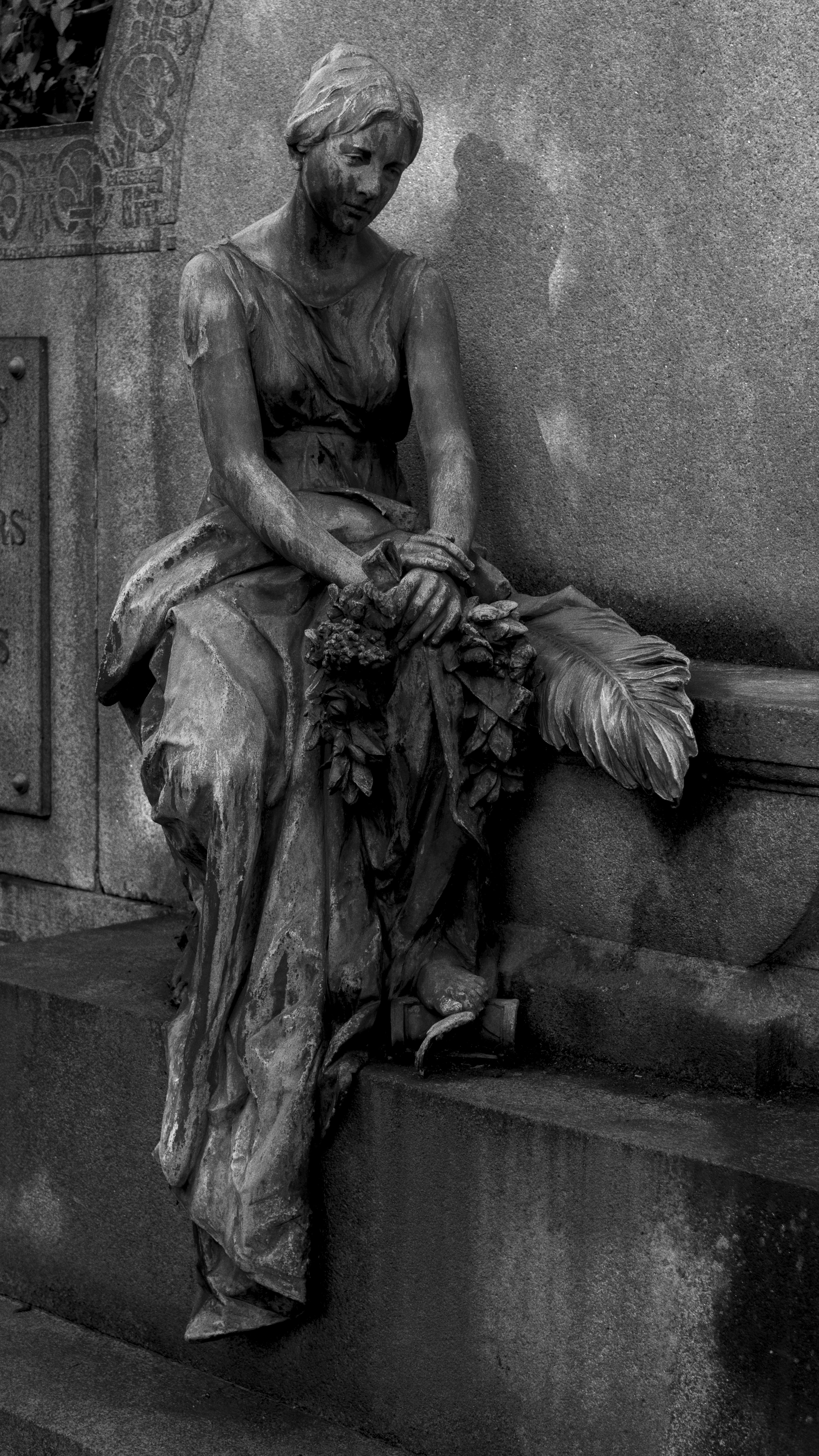 A stone statue of a woman holding a wreath