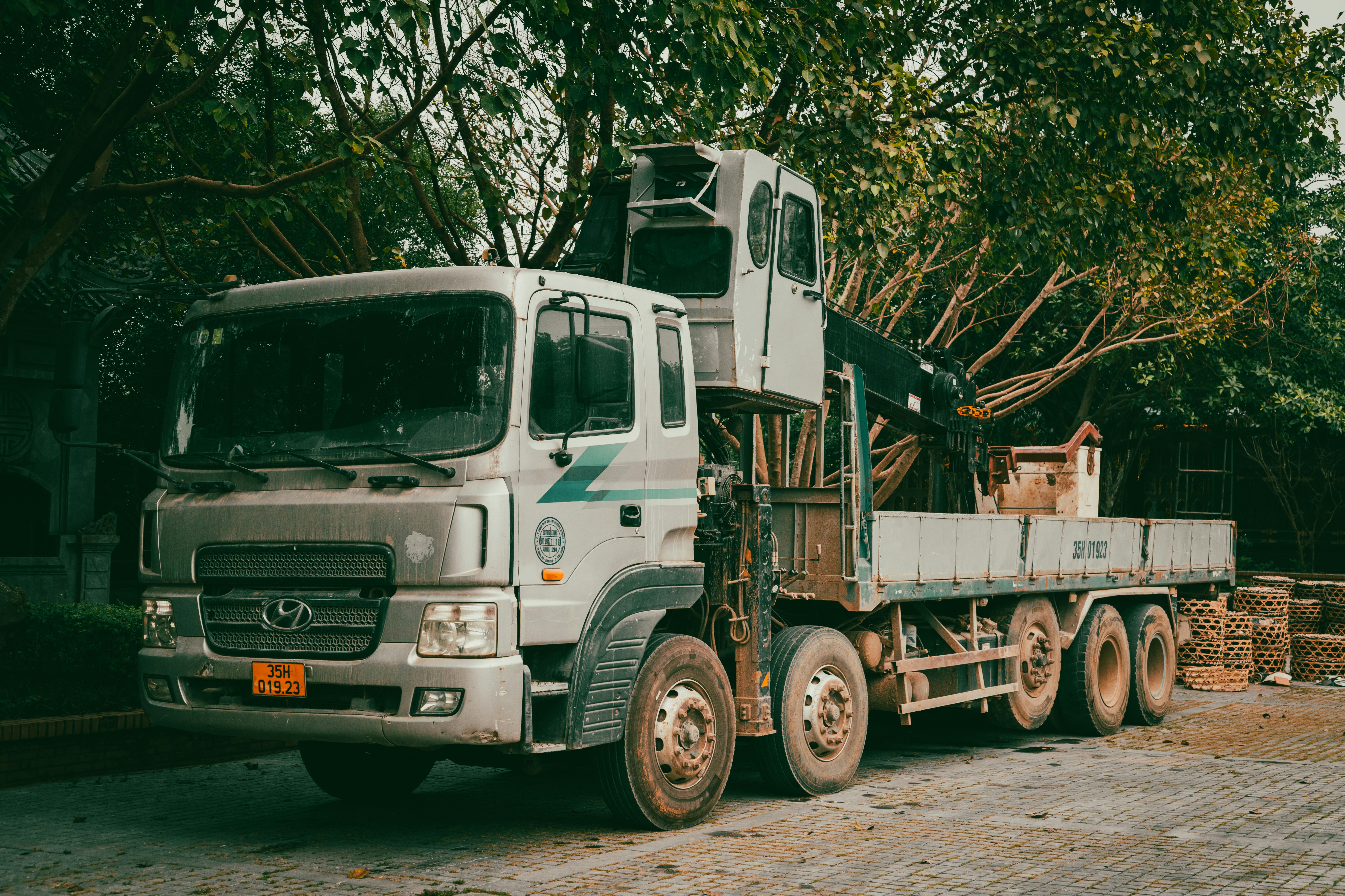 A white crane truck parked outdoors near trees.