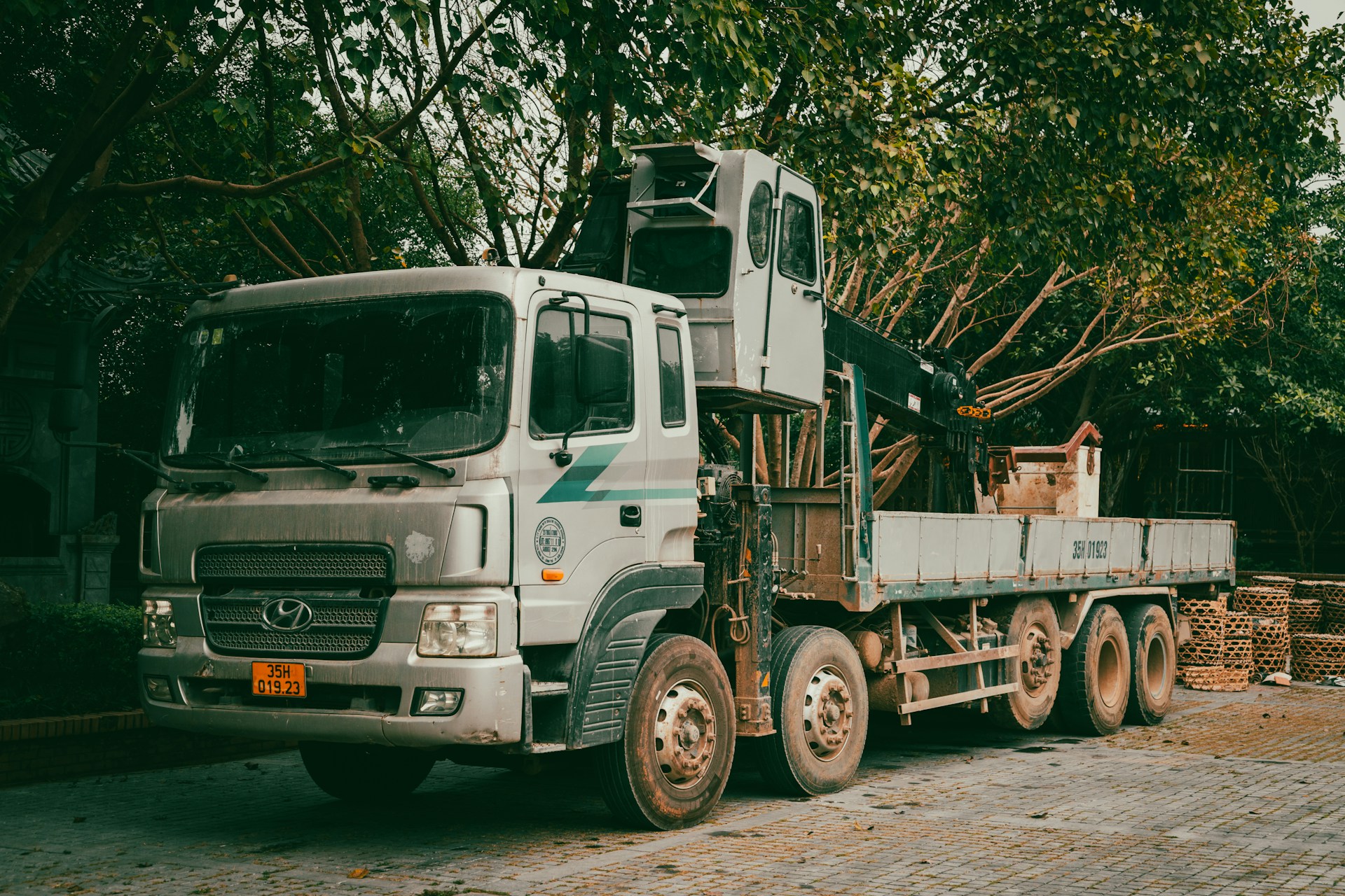 A white crane truck parked outdoors near trees.