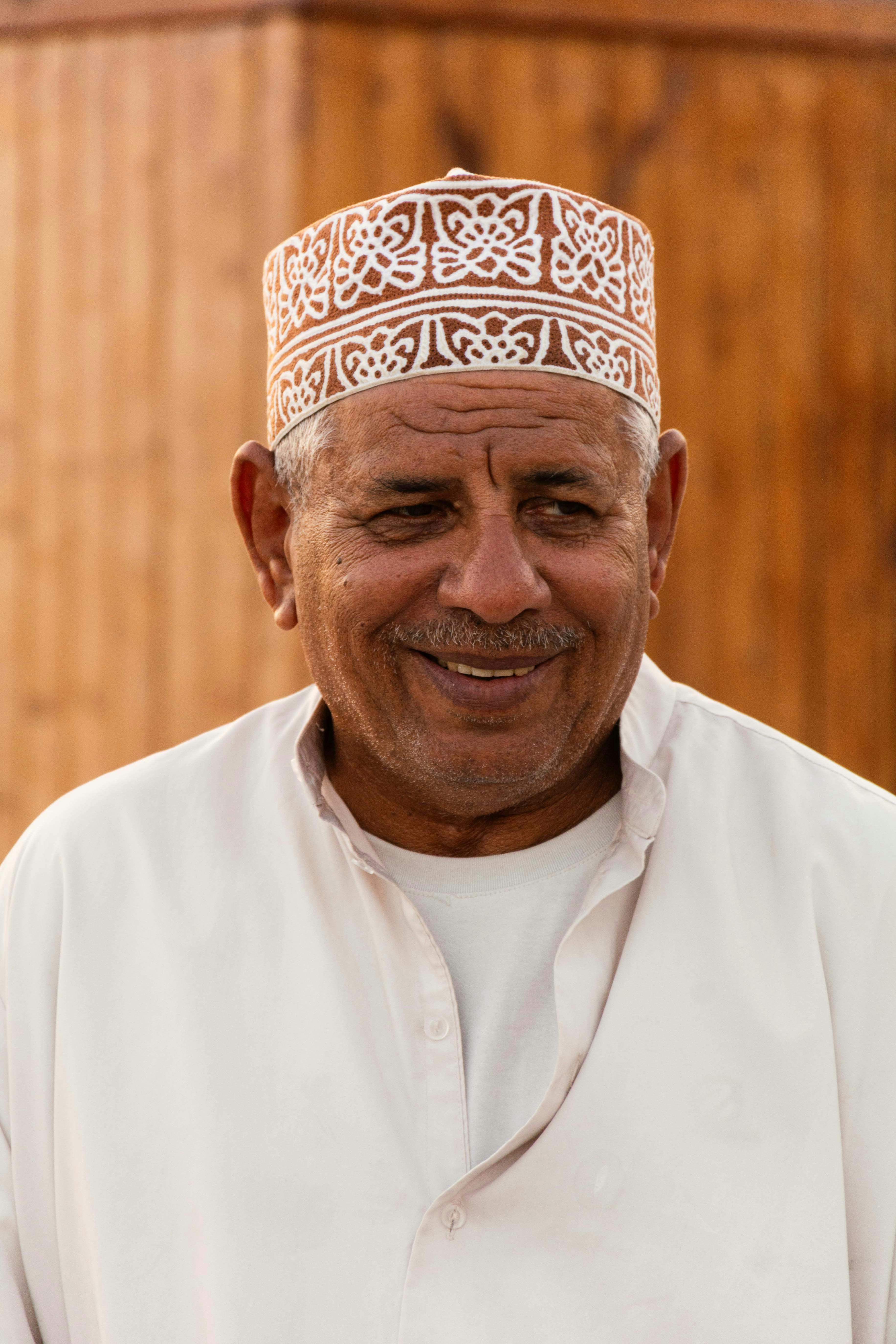 An elderly man wearing a traditional cap and white clothing